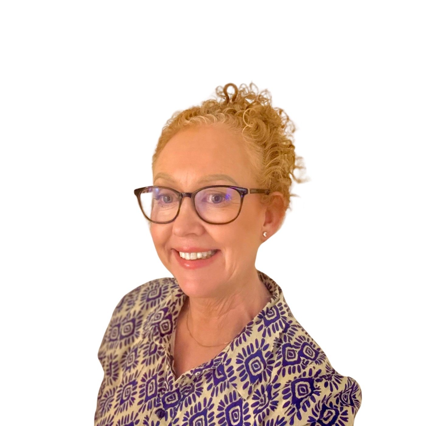 A woman with glasses and curly blonde hair in a bun, wearing a patterned shirt, smiling in front of a plain white background.