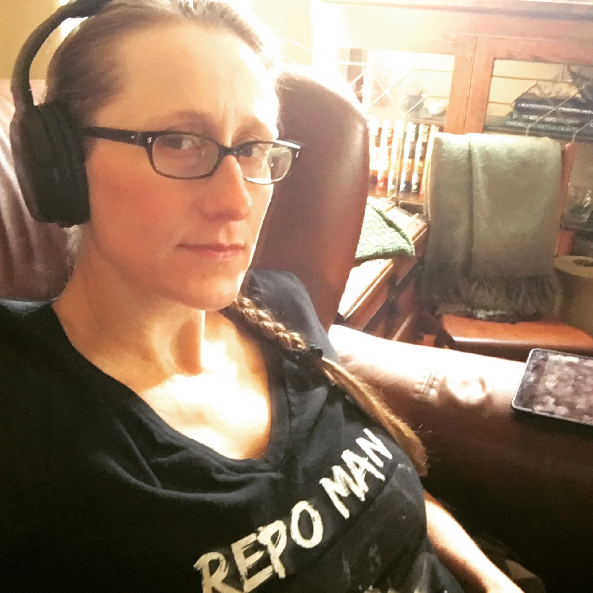 Amanda K. King, independent author of horror, science fantasy, and action adventure novels, wearing headphones. She is wearing a Repo Man t-shirt.