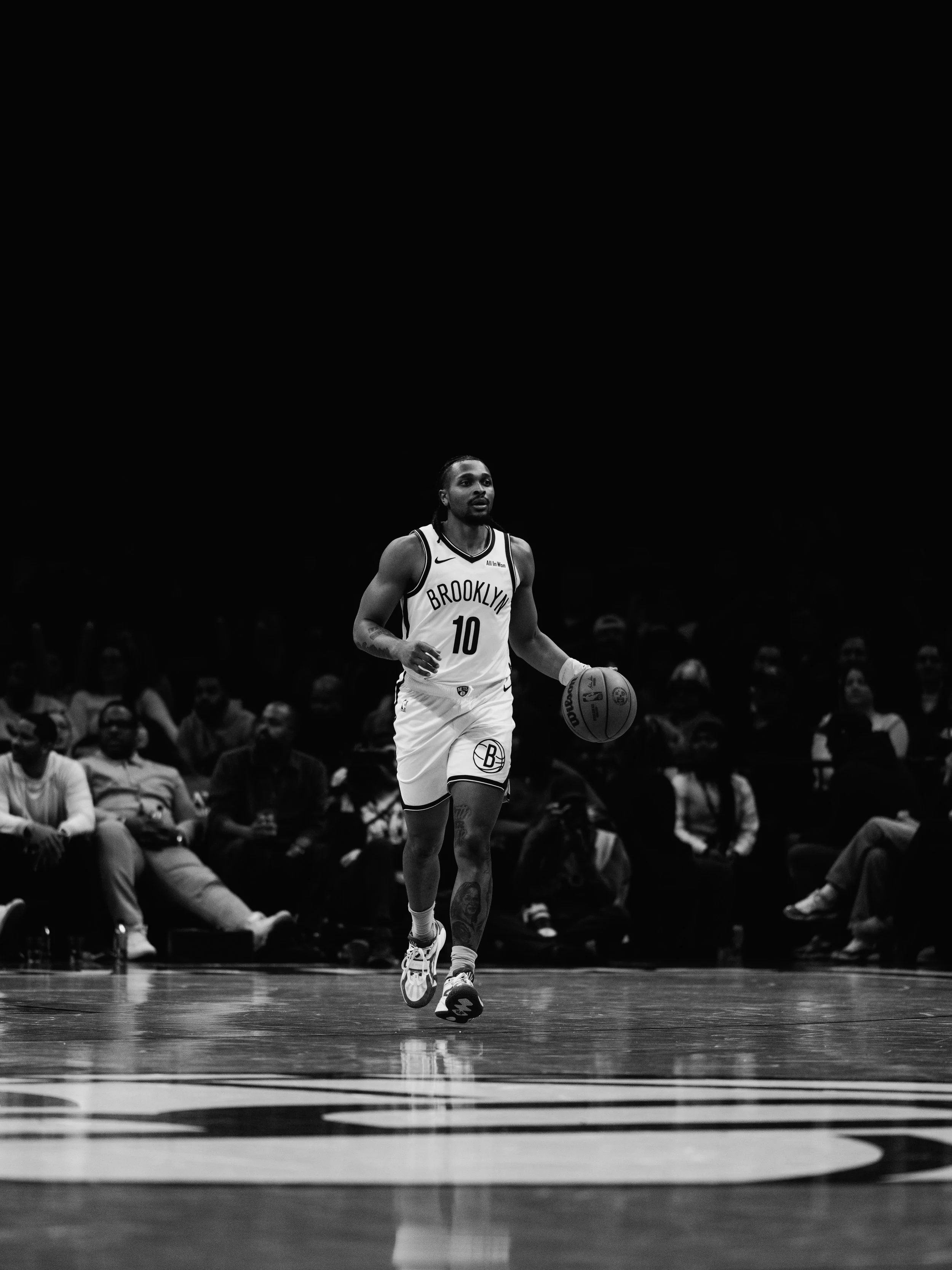 A basketball player wearing Brooklyn Nets uniform with the number 10 dribbling the ball on the court.