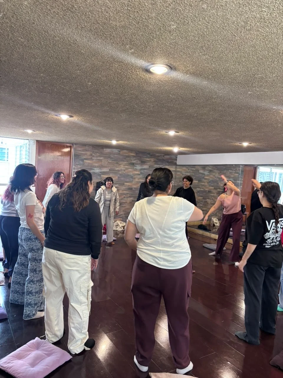 Grupo de personas participando en una clase de yoga o ejercicio en un salón interior.