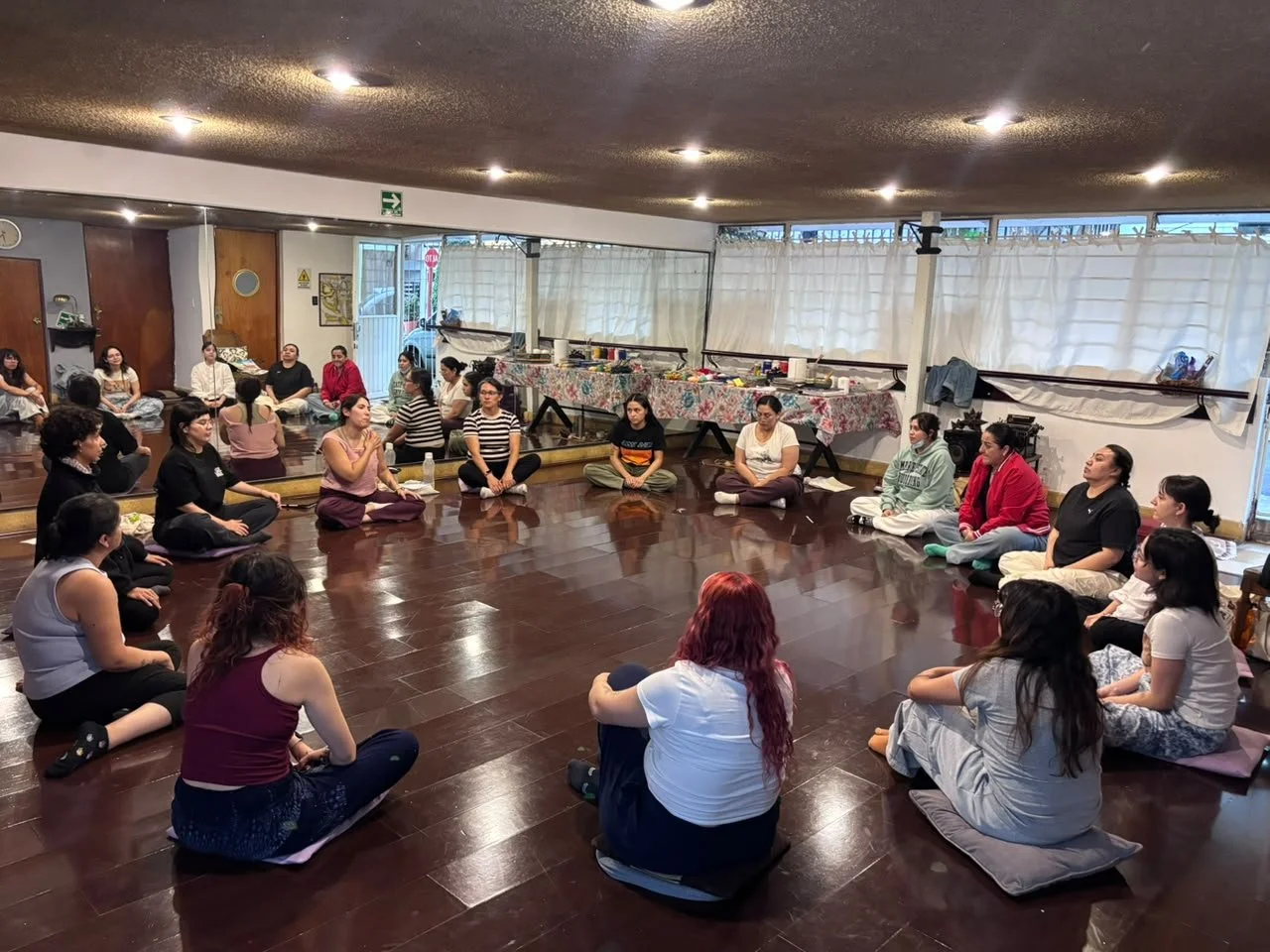 Grupo de mujeres sentadas en círculos en un espacio interior, participando en una actividad colectiva.
