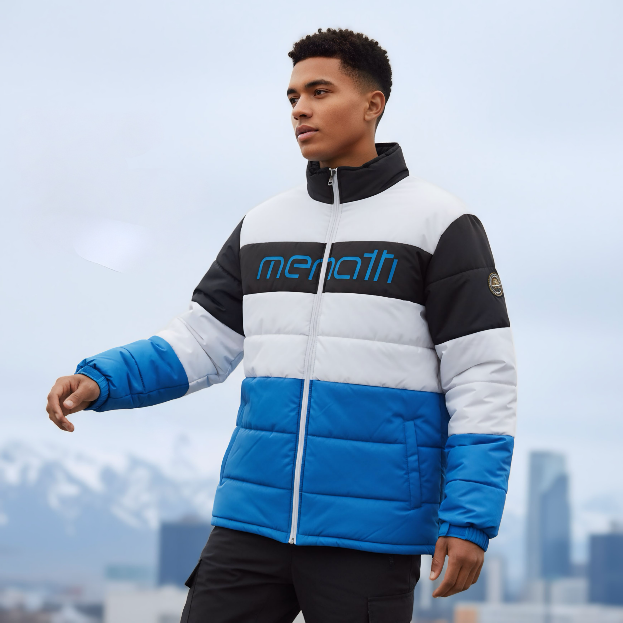 Young man in a color-blocked puffer jacket outdoors with a city skyline and mountains in the background.