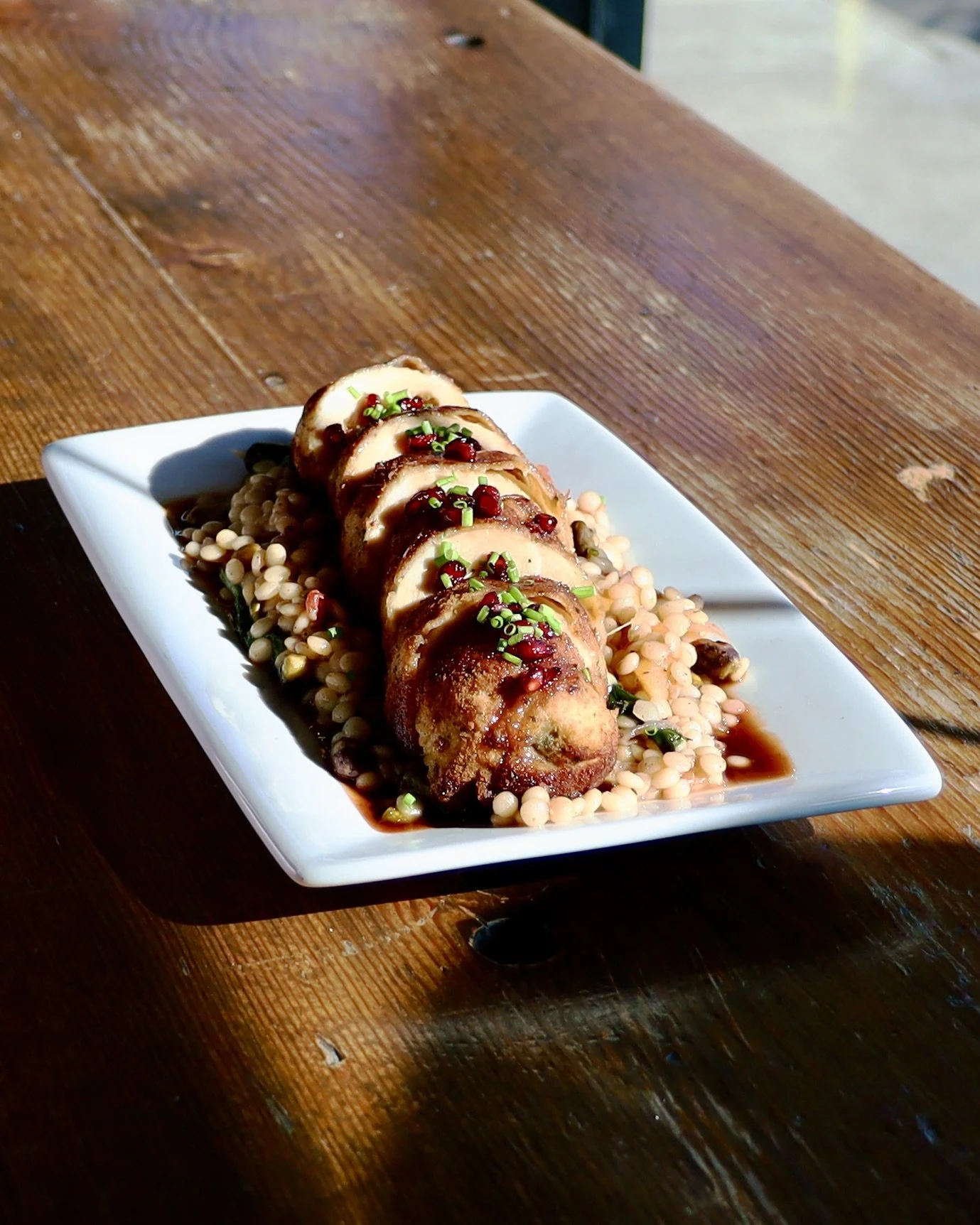 Gouda + Spinach Stuffed Chicken served over pearl couscous with apricot, pistachio, roasted tomato and caramelized onion, finished with housemade pomegranate glaze.