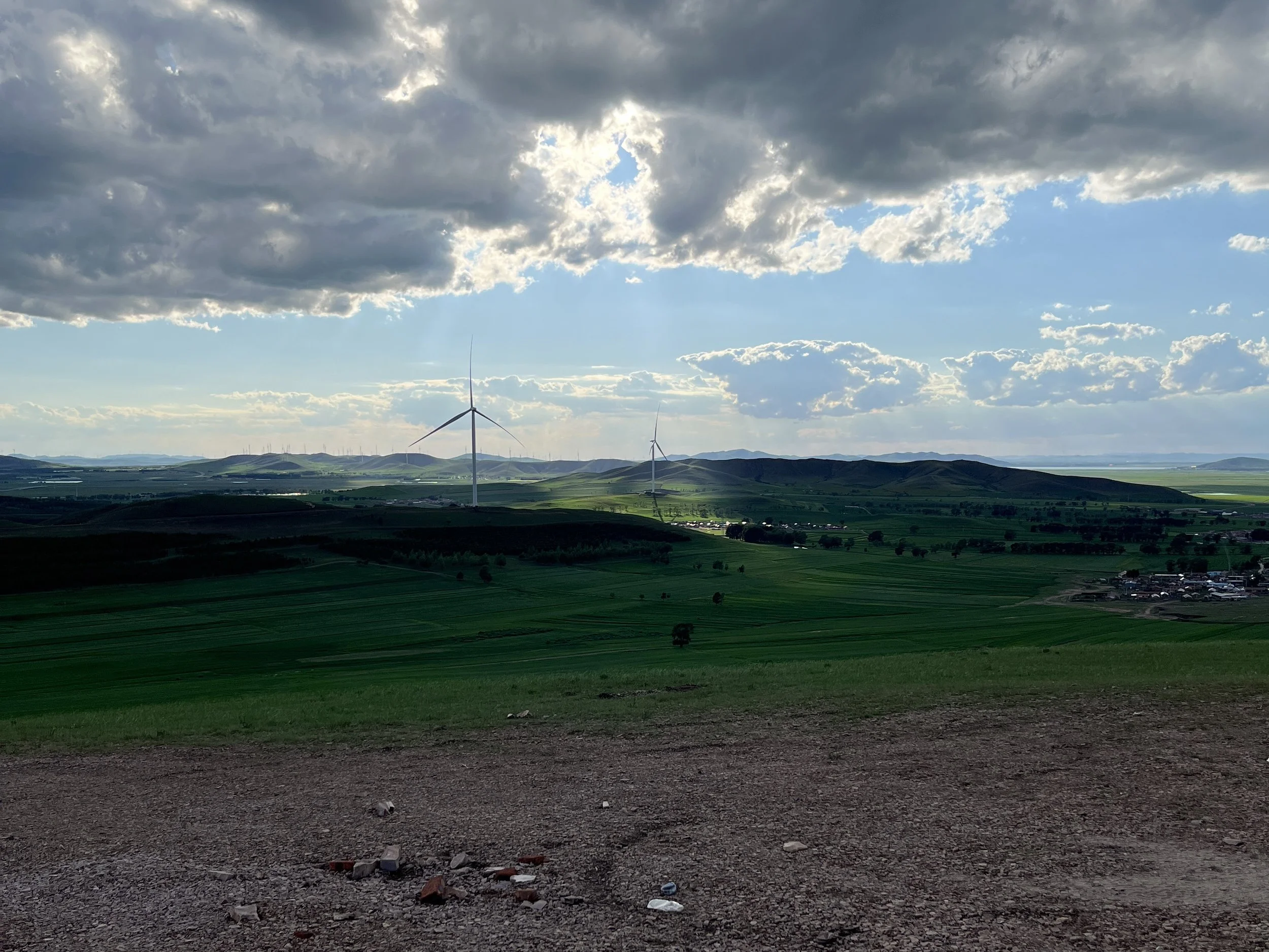 Sunshine pokes through the clouds highlighting wind turbines.