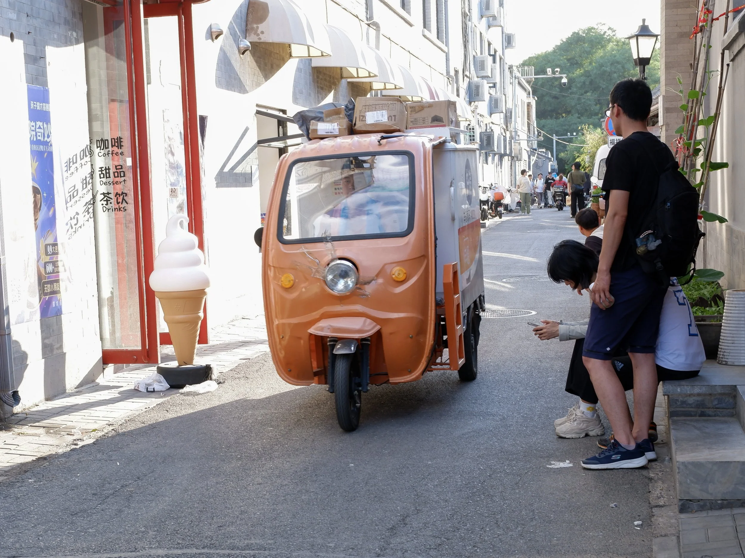 A delivery scooter zips by in Nanluoguxiang.