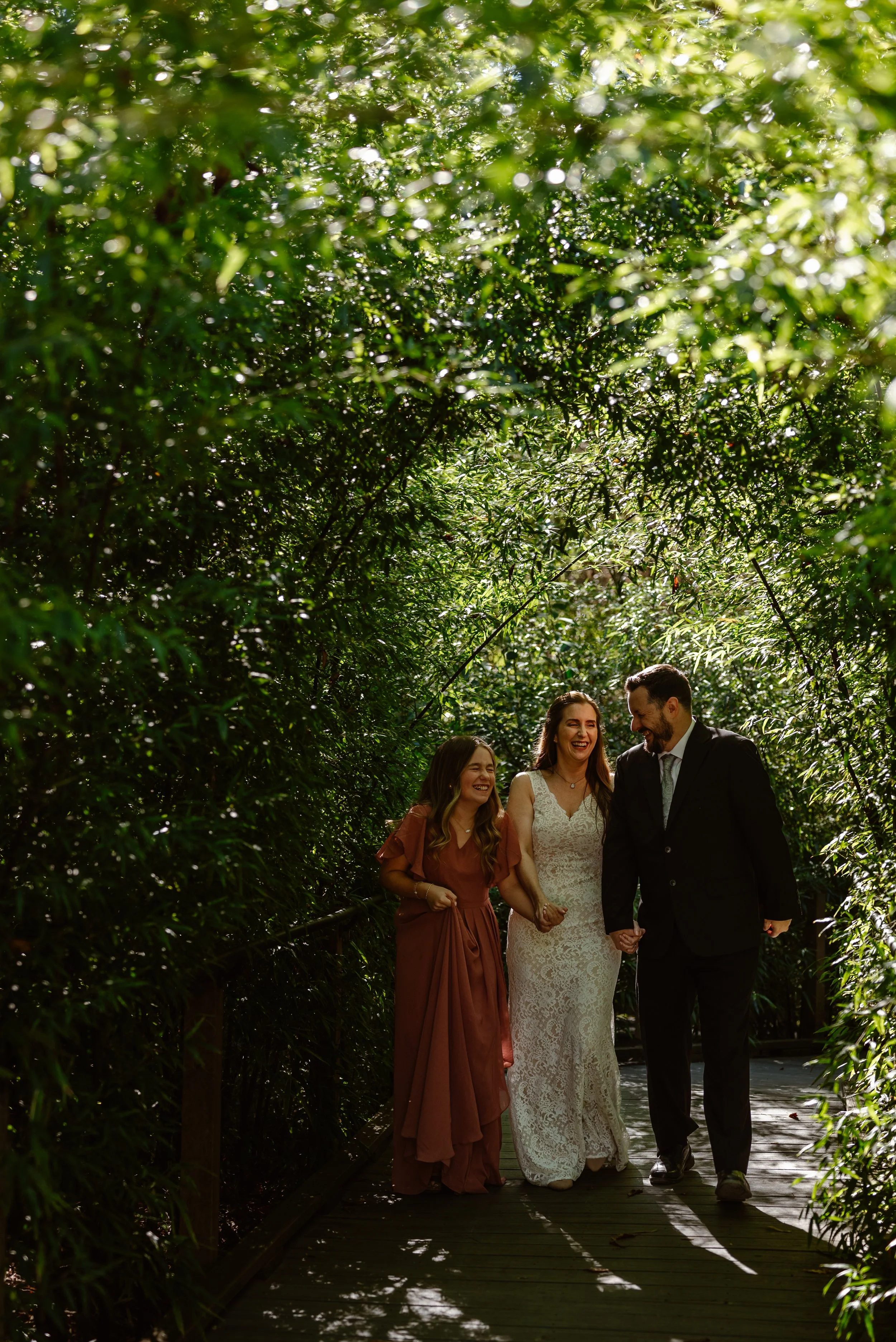 A family walks through a bamboo tunnel during an outdoor adventure elopement at the Birmingham Botanical Gardens