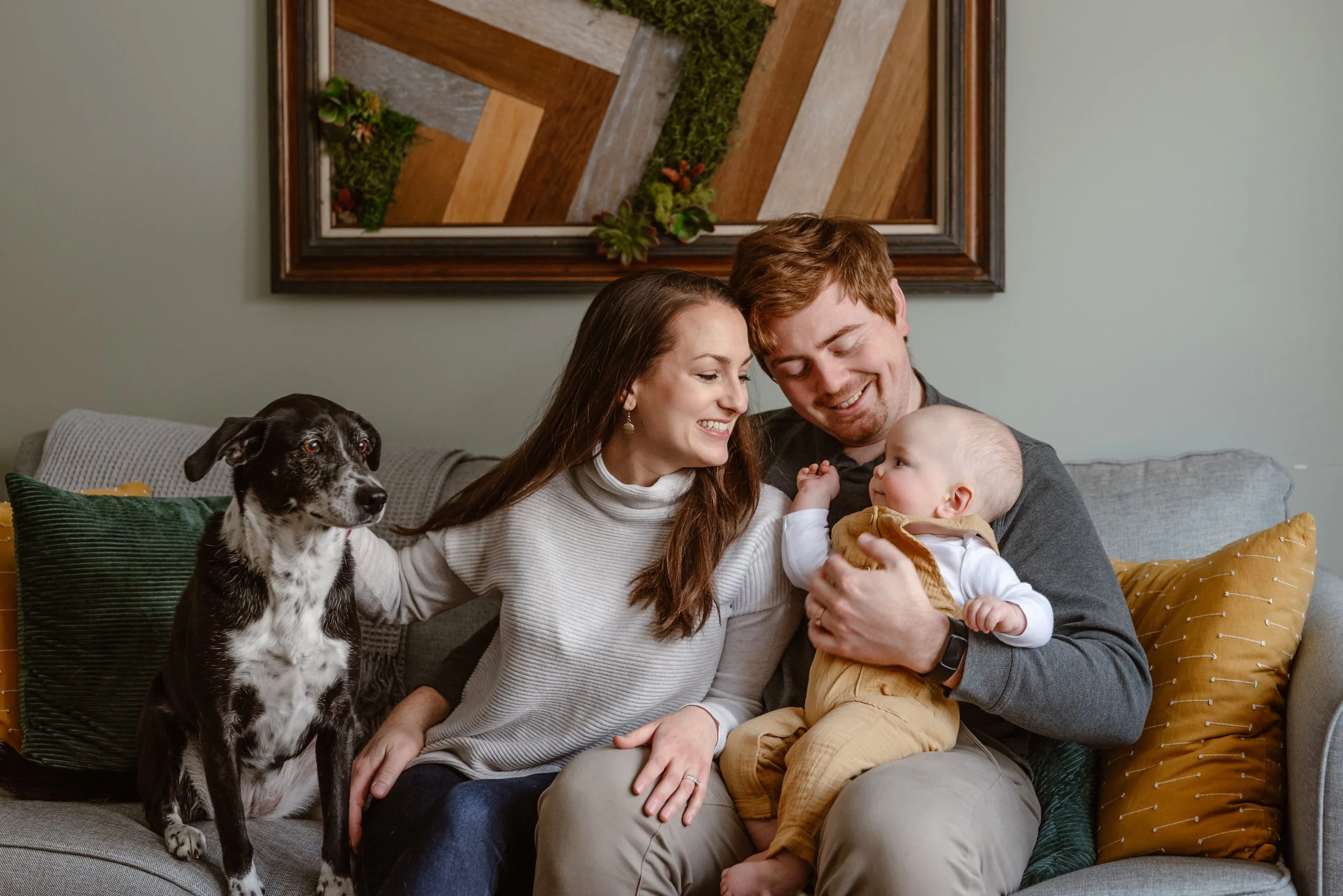 Two parents smiling and looking at their baby during a lifestyle family photoshoot.