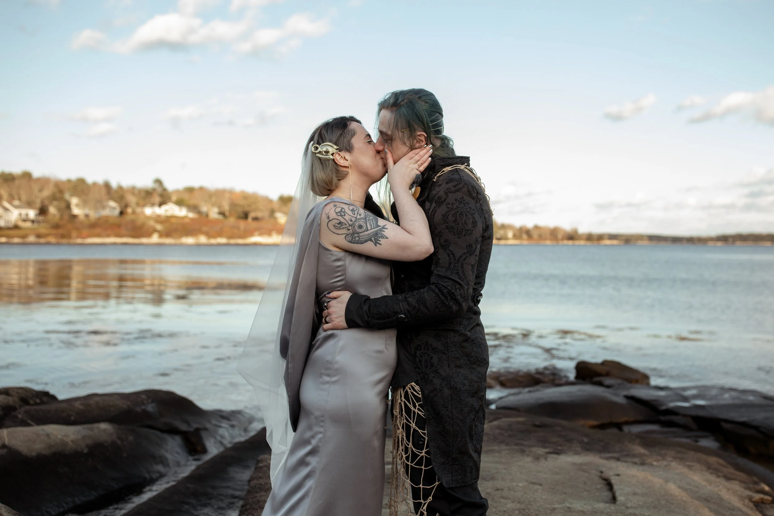 A couple kisses during a fall beach adventure elopement in Maine