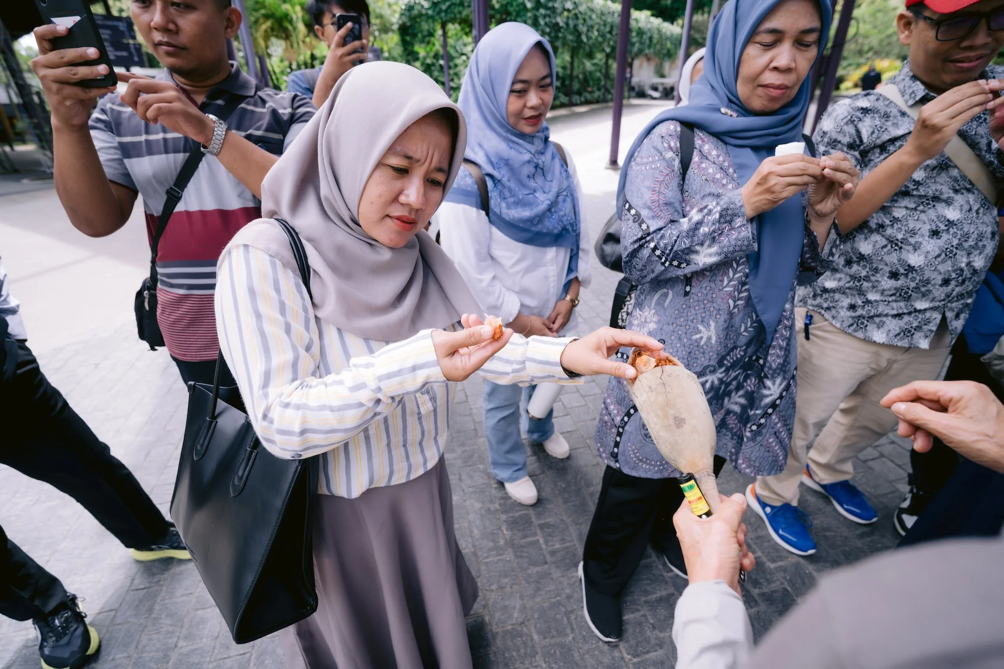 A guide from Gardens by the Bay showing the participants a seedpod from a plant
