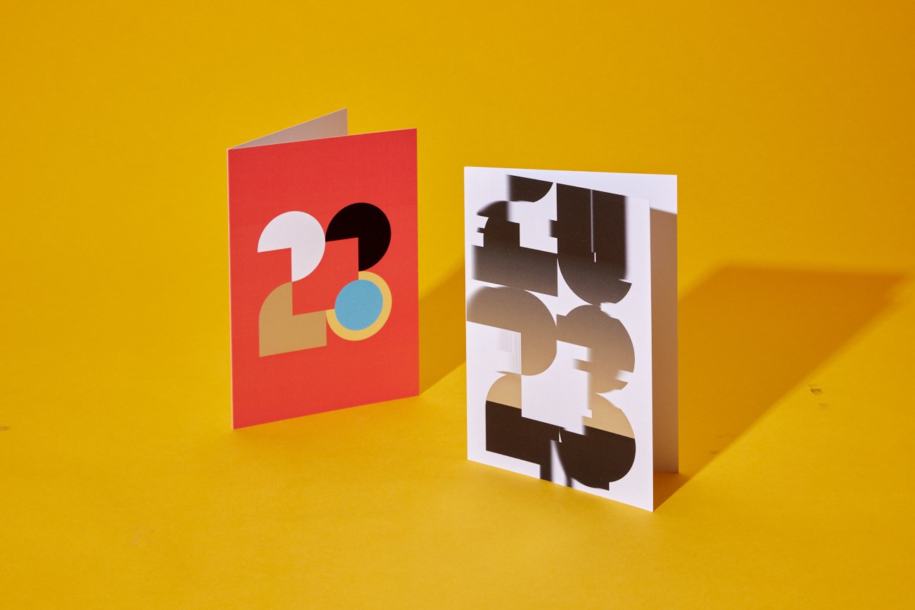 Colorful greeting cards with bold, abstract designs on a yellow background.