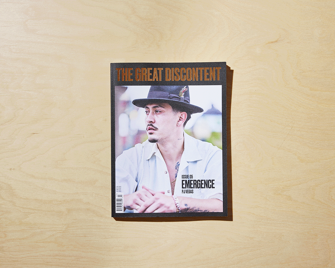 Magazine titled "The Great Discontent" featuring a man with a mustache and goatee, wearing a dark hat with a feather, a white shirt, and tattoos on his chest and hands.