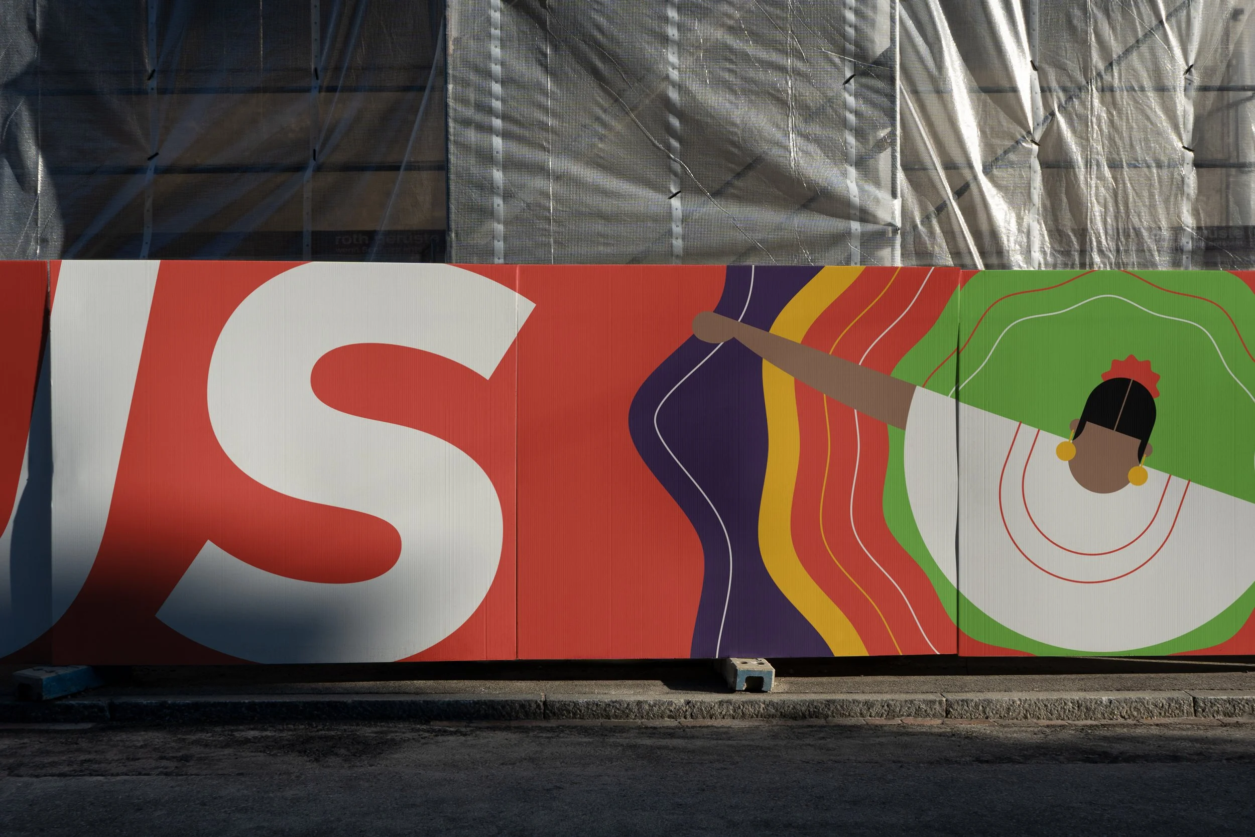 Partial view of a colorful street art mural with large letters and an illustration of a woman with a bun, earrings, and a floral headband, pointing with an extended arm.