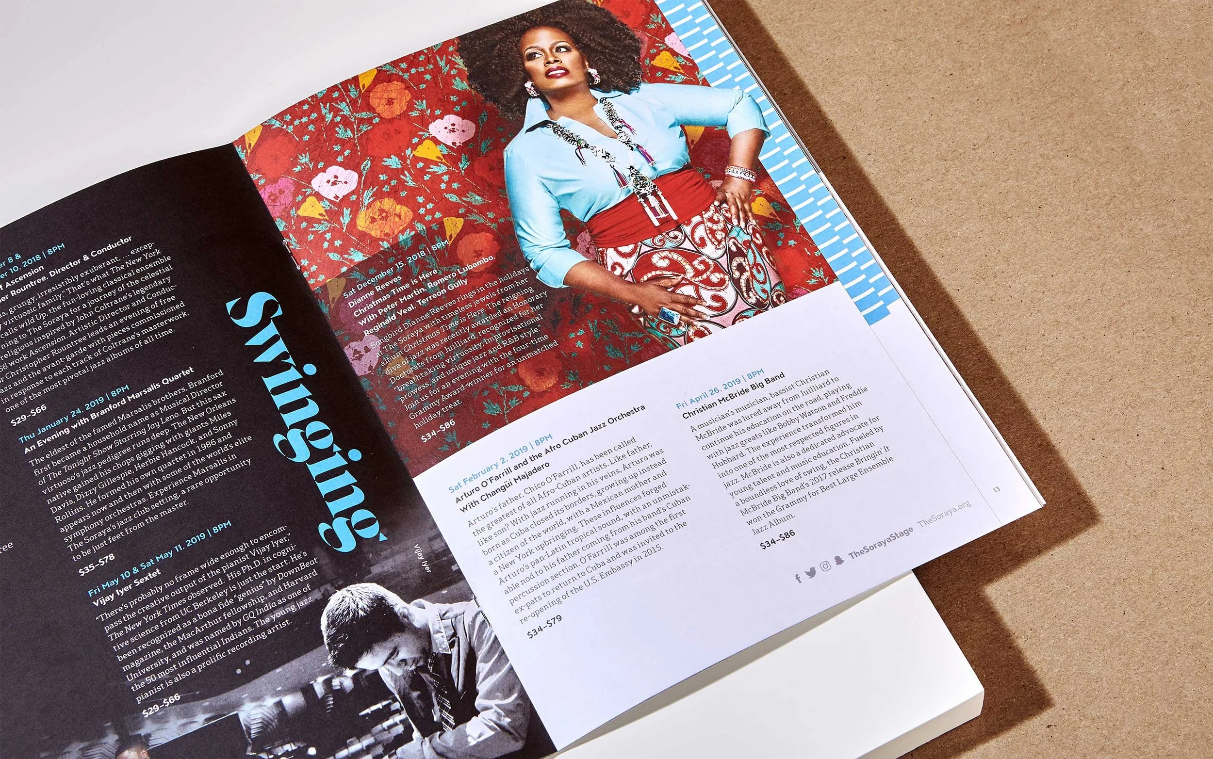 Open magazine showing a colorful woman in a blue blouse and patterned skirt sitting against a vibrant red floral background, with text about upcoming jazz performances and events.