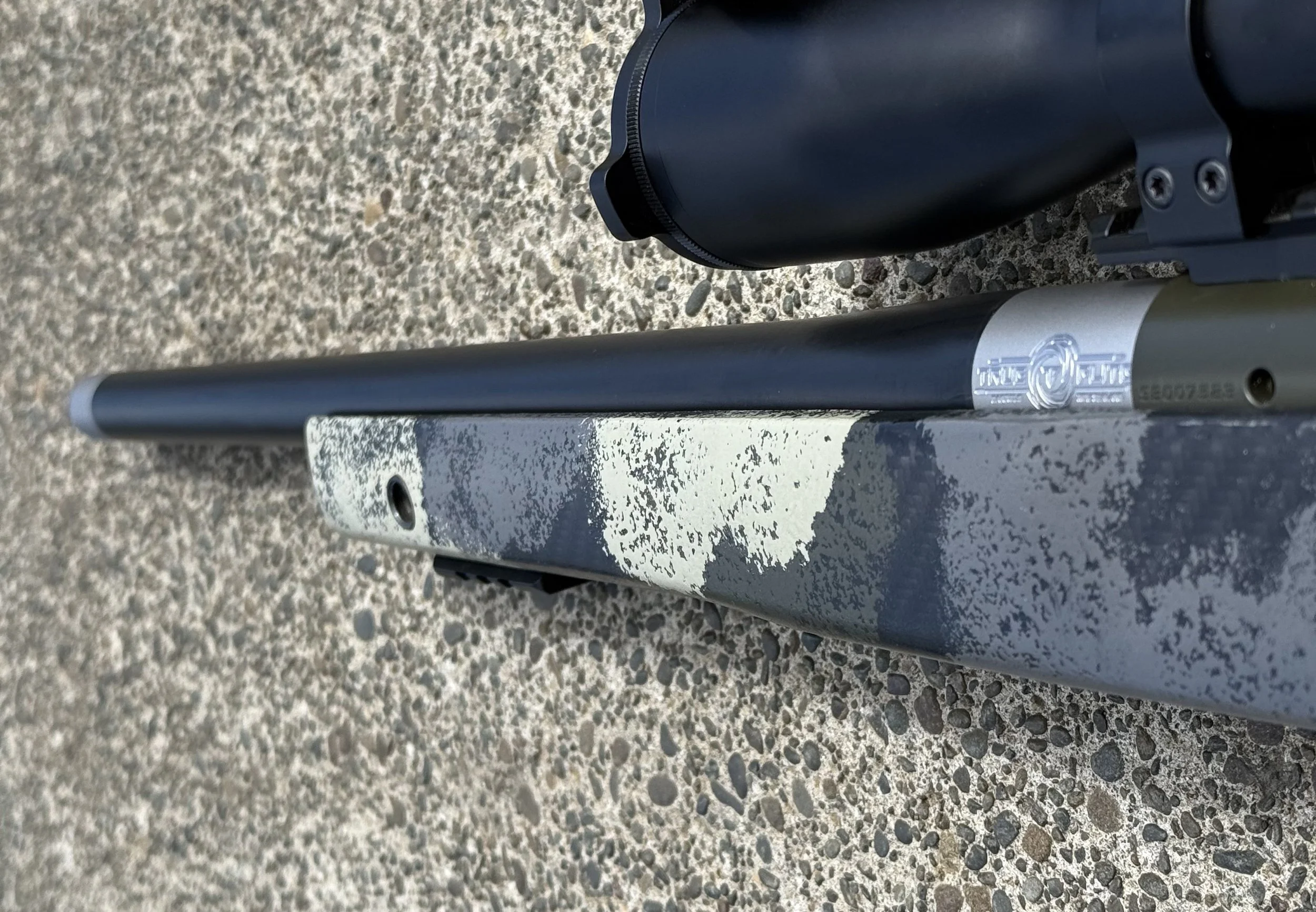 Close-up of a black camera and a gray metal object on a textured concrete surface.