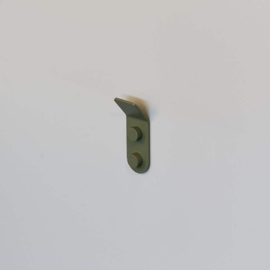 Minimalist green aluminum wall hook photographed in a studio for a product shot.