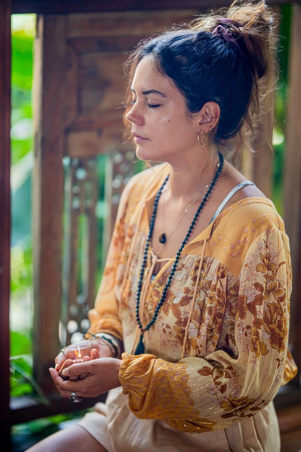 Charlotte meditating with a candle in a serene setting.