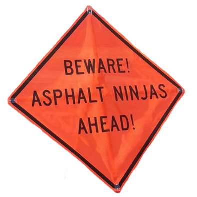 Orange traffic sign that says Beware! Asphalt Ninjas Ahead!. Road work sign on page that is broken.