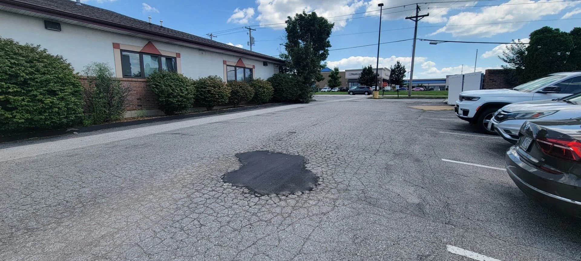 Parking lot with a pot hole replaced with fresh asphalt