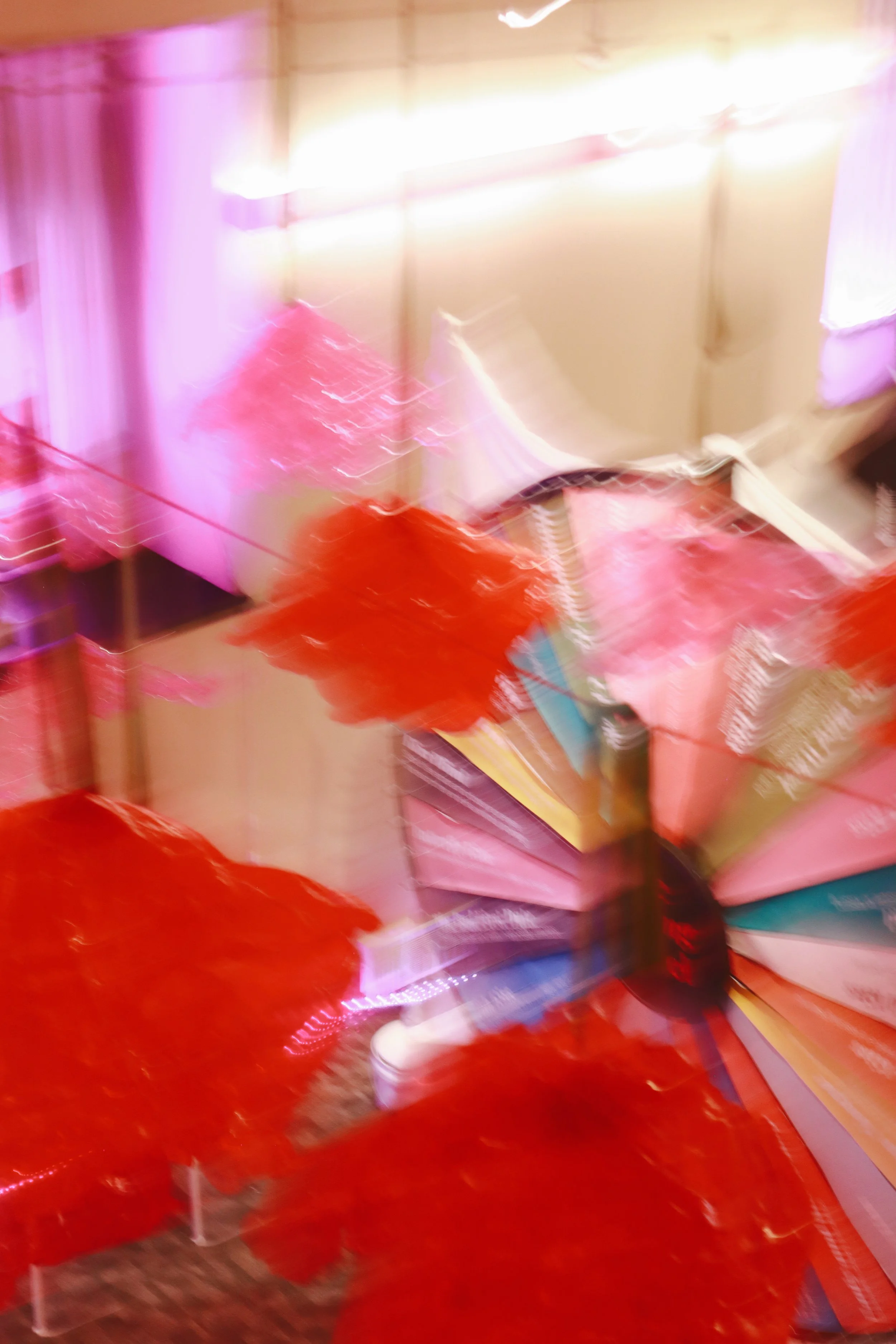 Blurry photo of colorful umbrellas, possibly in a store or market setting. The Valentine's Museum NYC Valentine's Day Event.