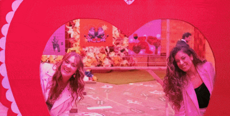 Two women pose in a heart-shaped mirror at The Valentine's Museum NYC Valentine's Day Event.
