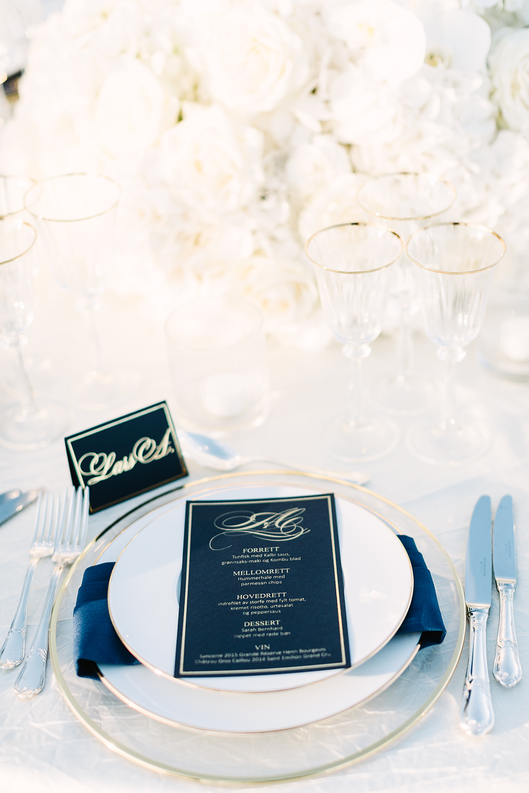 Beautiful gold detailed dinner setting, navy blue menu with gold foil and white flowers.