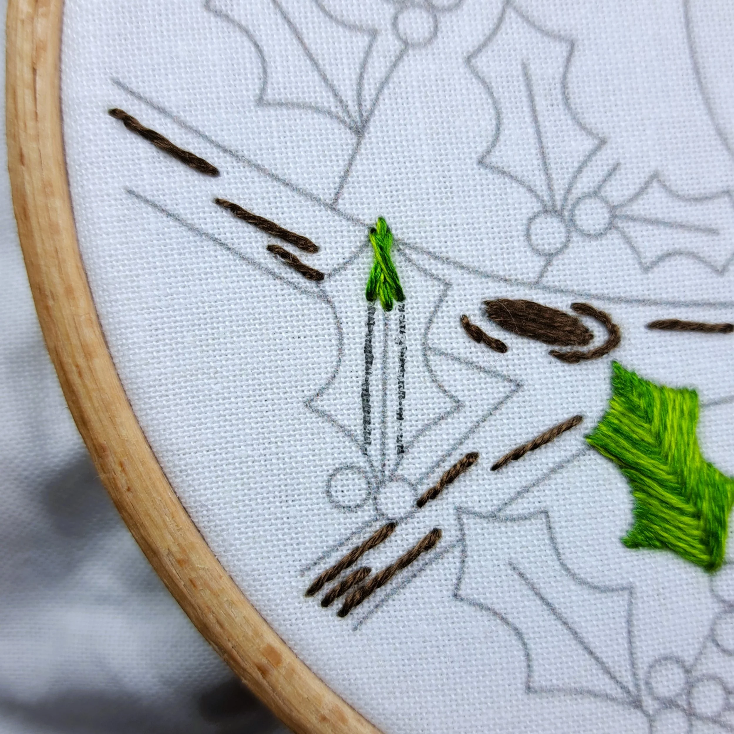 Close-up of the first green Fishbone Stitches at the top of a holly leaf.
