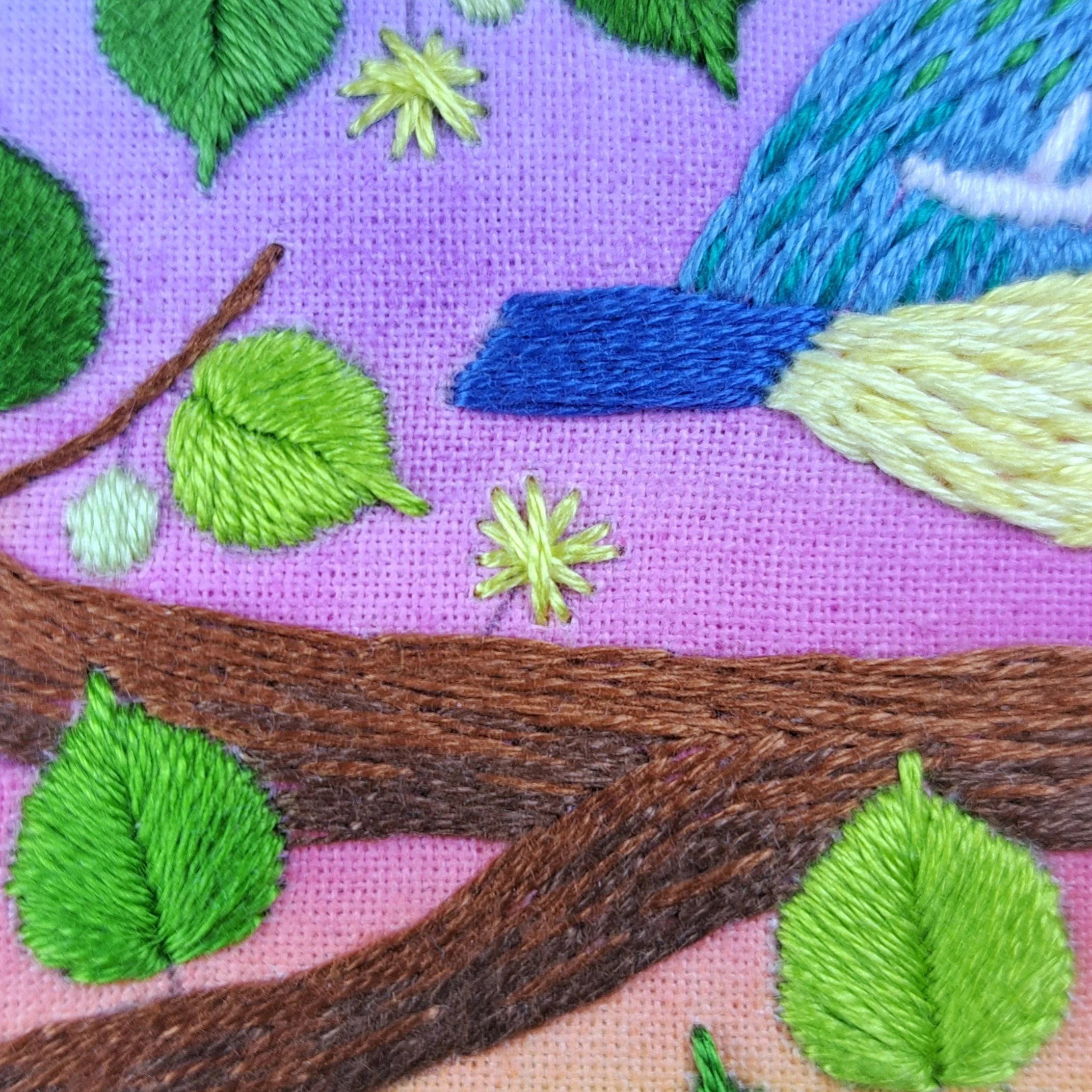 Close-up of the yellow Straight Stitches used to embroider the flowers on the tree branch.