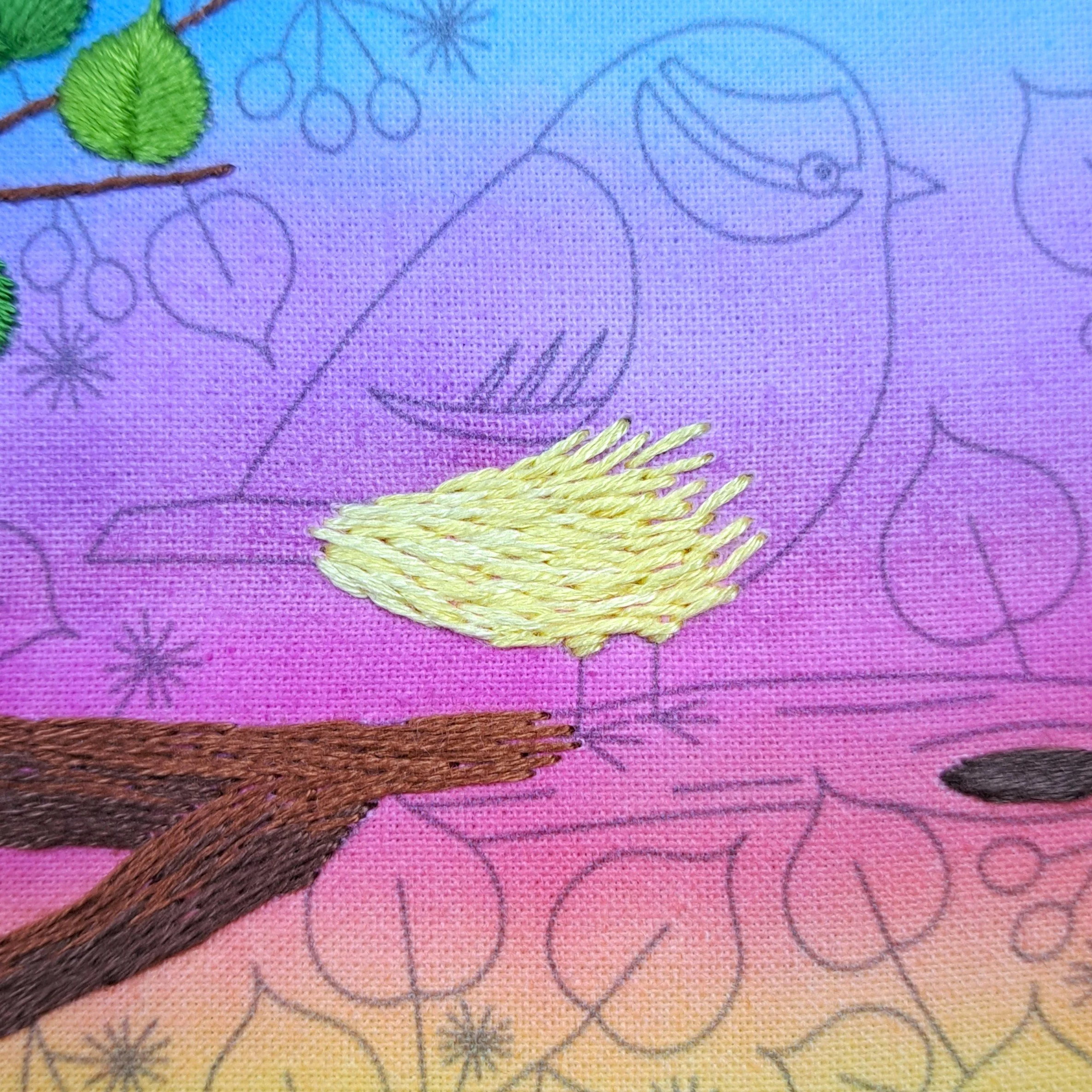 Close-up of the mid yellow Long and Short Stitch used to embroider the feathers on the Blue Tits belly. These stitches are blending into the lighter yellow stitches.