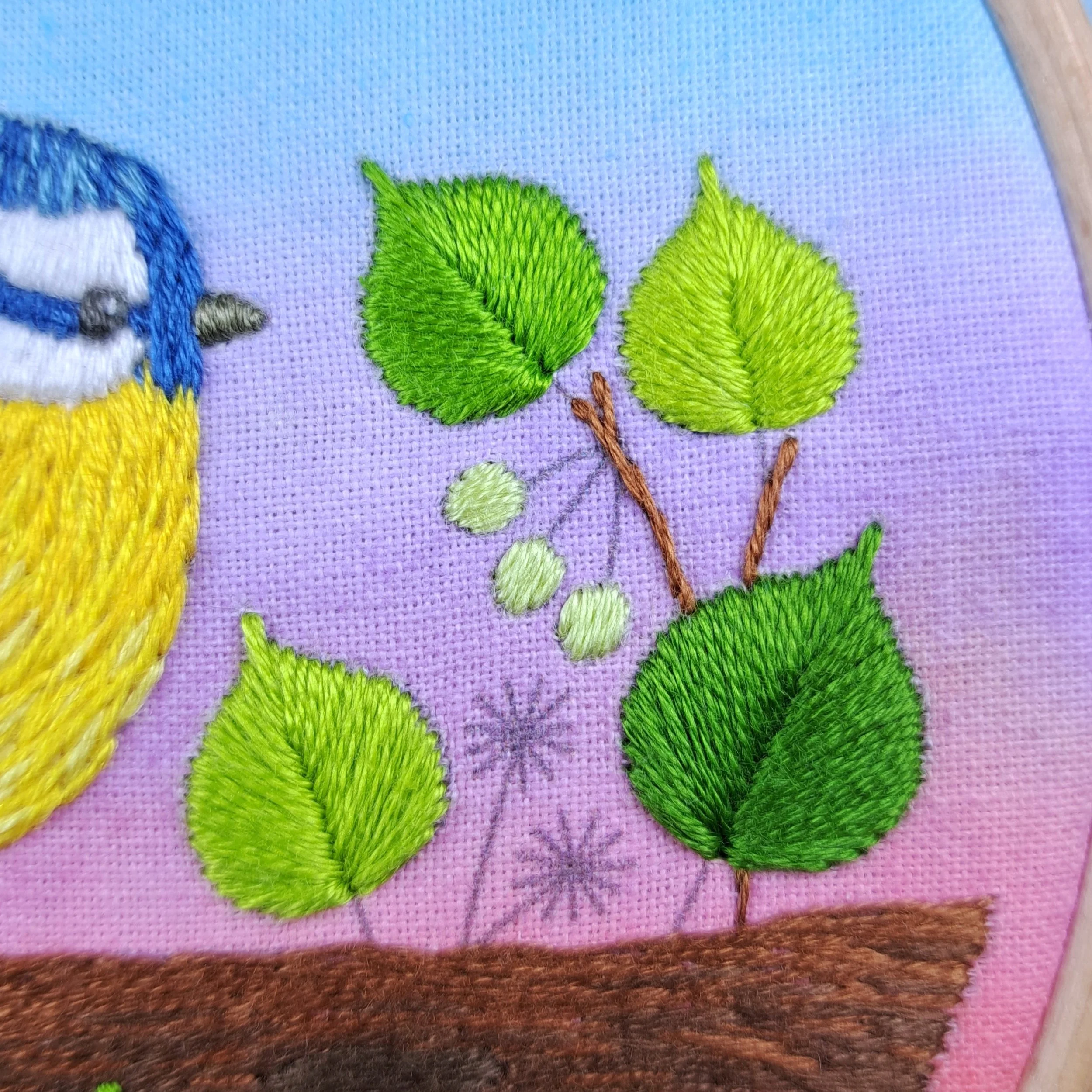 Close-up of the pale green Satin Stitches used to embroider the flower buds on the tree branch.