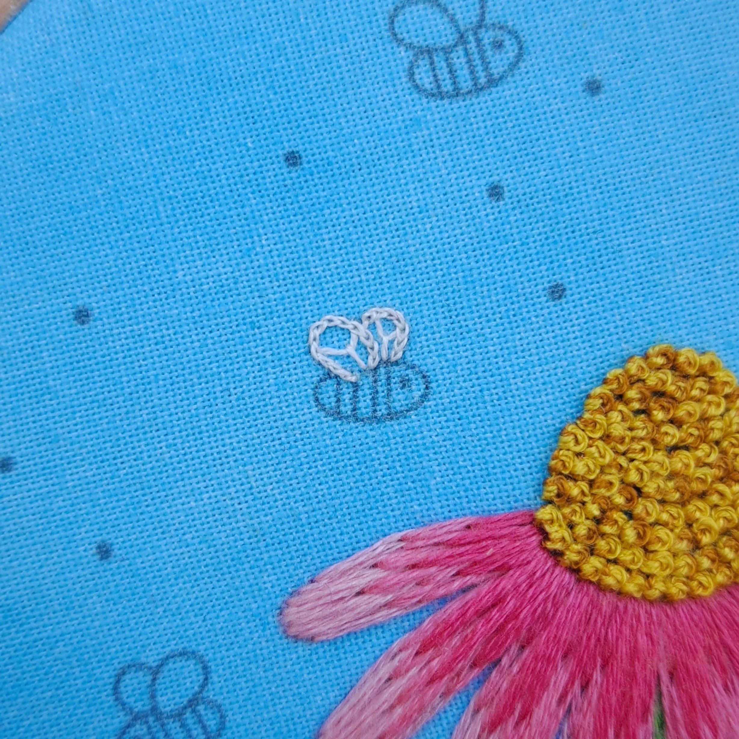 Close-up of the white Split Stitch used to embroider the outline of the smaller bees wing.