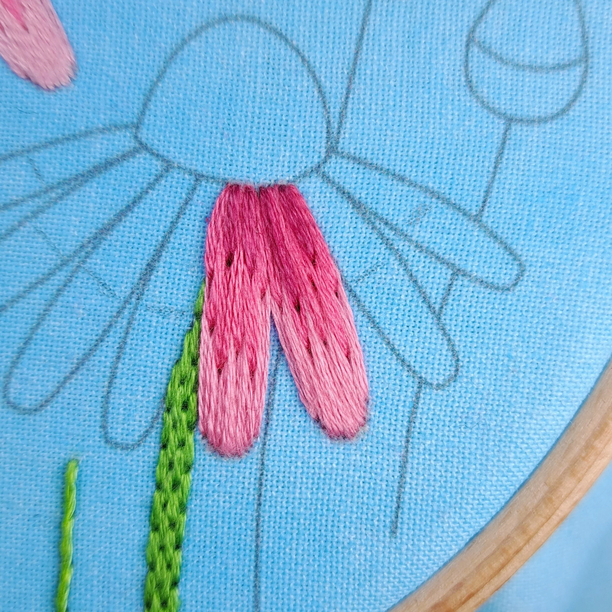 Close-up of dark pink Straight Stitches embroidered on to each of the right-hand echinacea flower petals.
