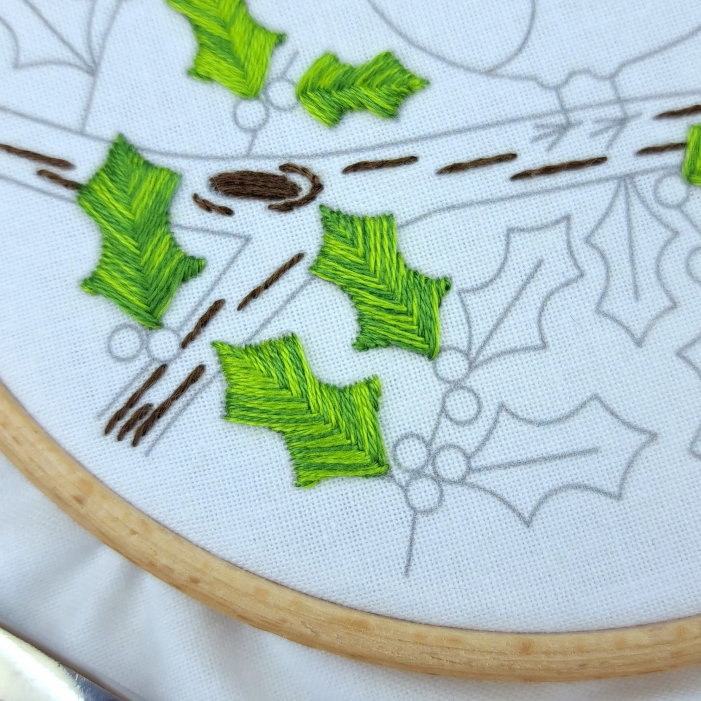 Close-up of two fully stitched holly leaves using green Fishbone Stitch.