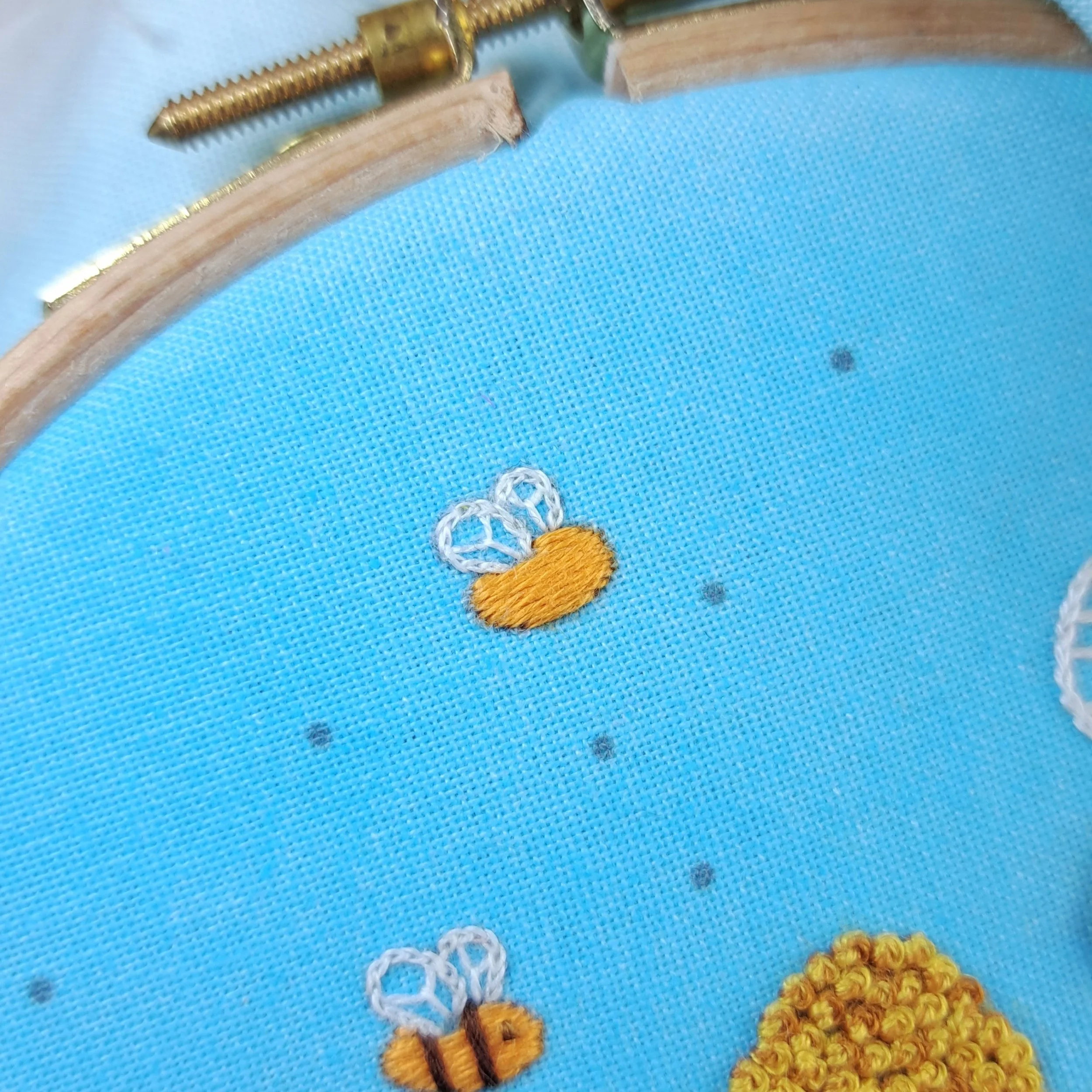 Close-up of the orange Satin Stitch used to embroider the smaller bees body.