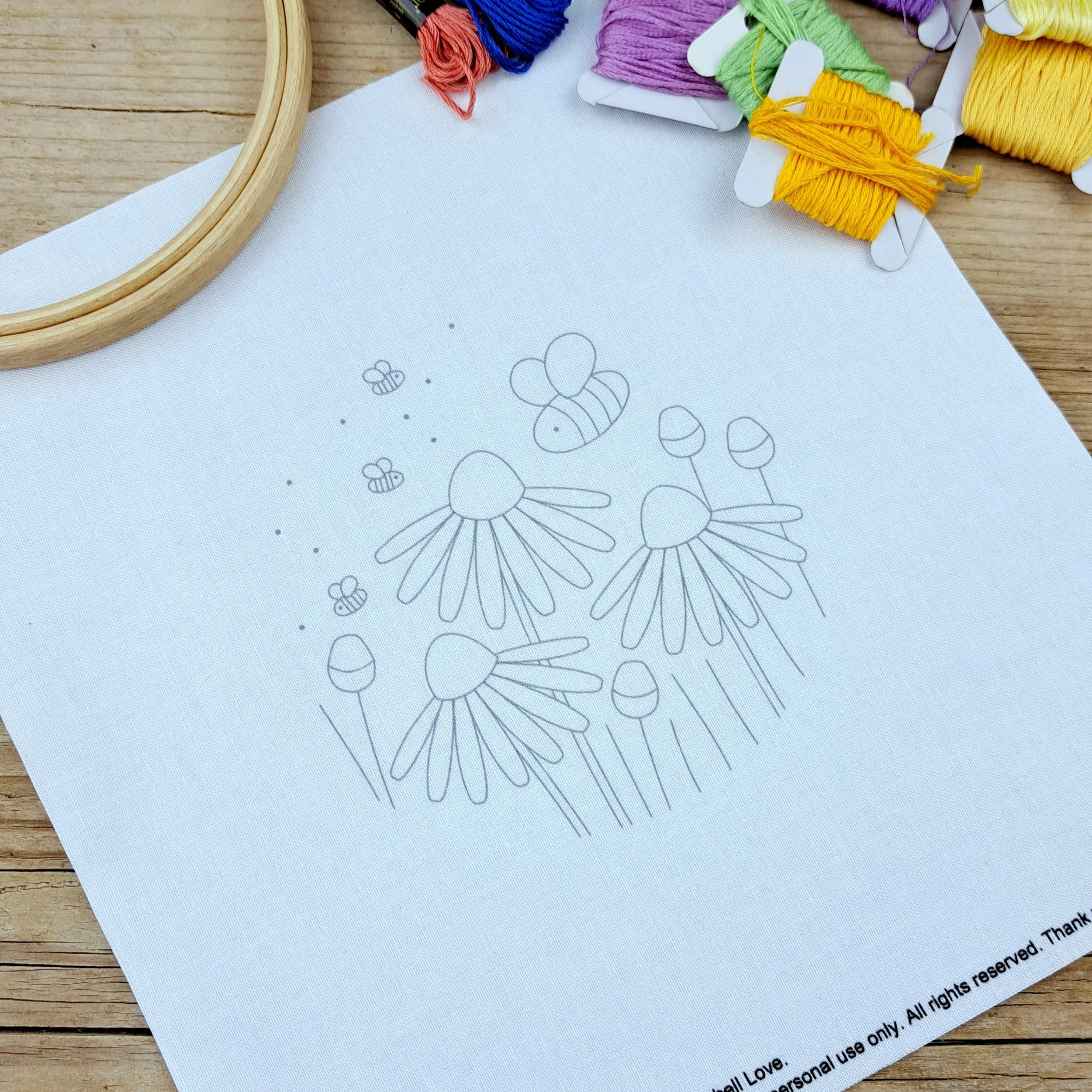 Fabric embroidery panel with the unstitched flowers, buds and bees design. The outlines of the design are in grey.