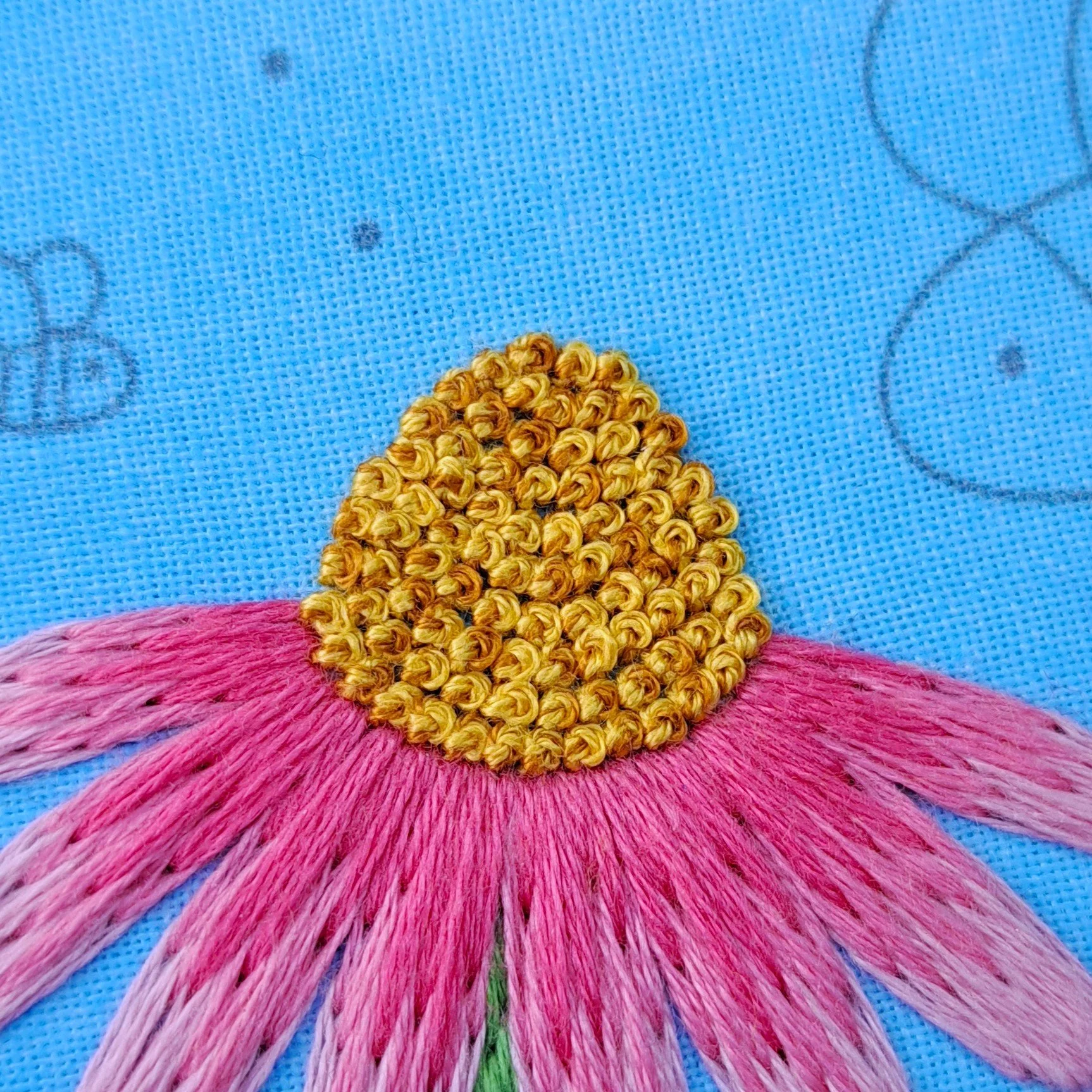 Close-up of golden French Knots used to embroider the centres of the Echinacea flowers.