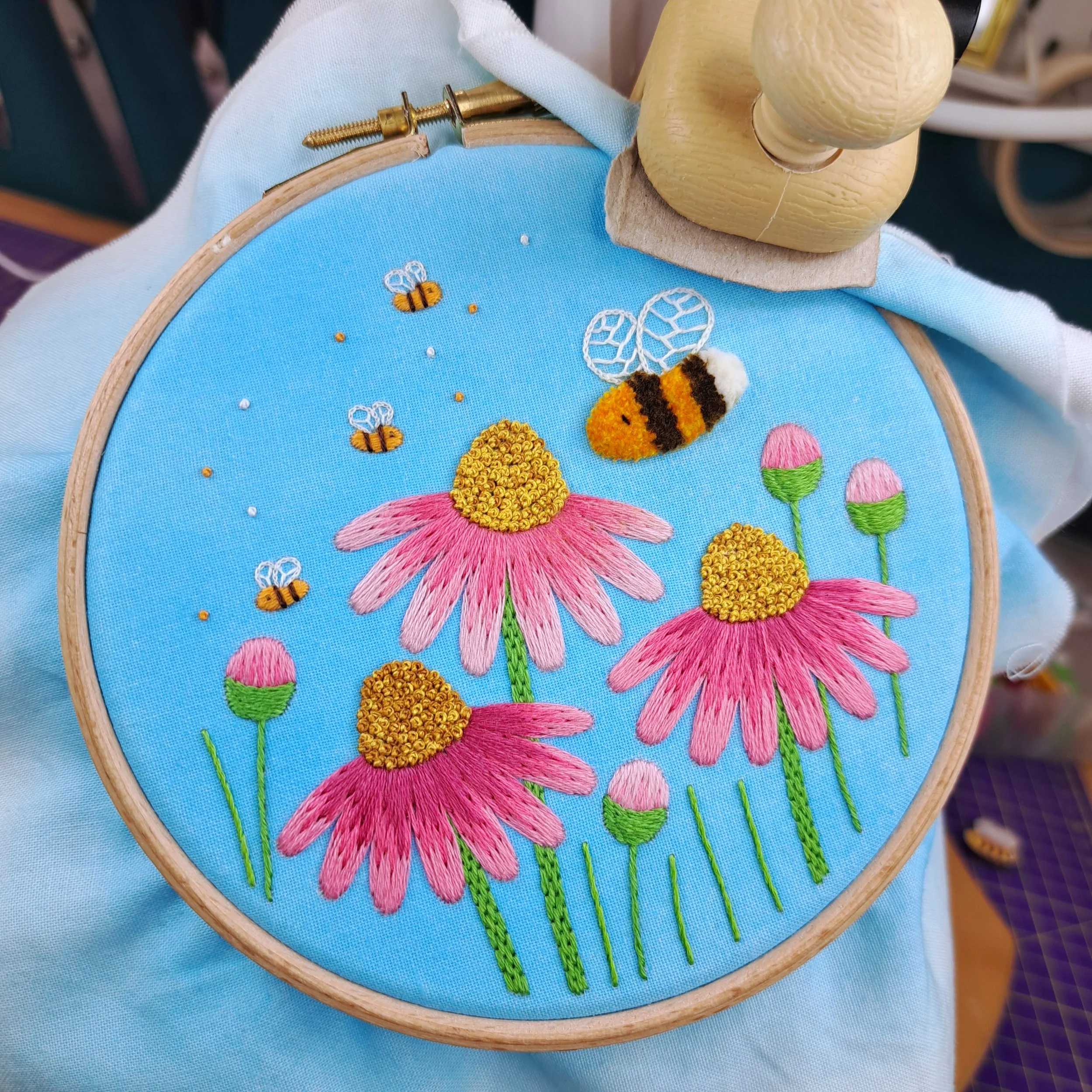 Finished embroidery of pretty flowers, buds and bees. The distant bees are stitched in orange and white.