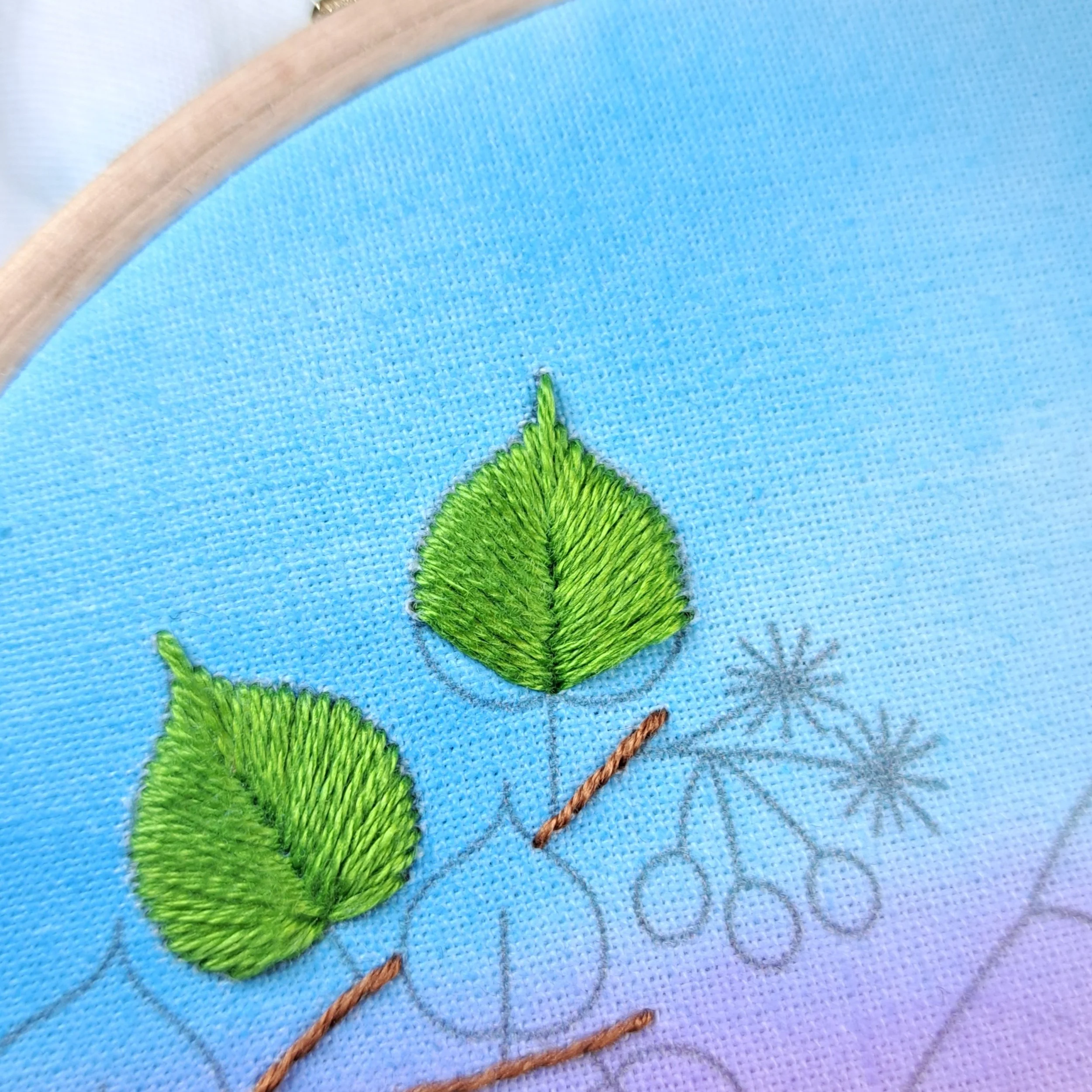 Close-up of the half completed green Leaf Stitch used to embroider the lime leaves on the tree branch.