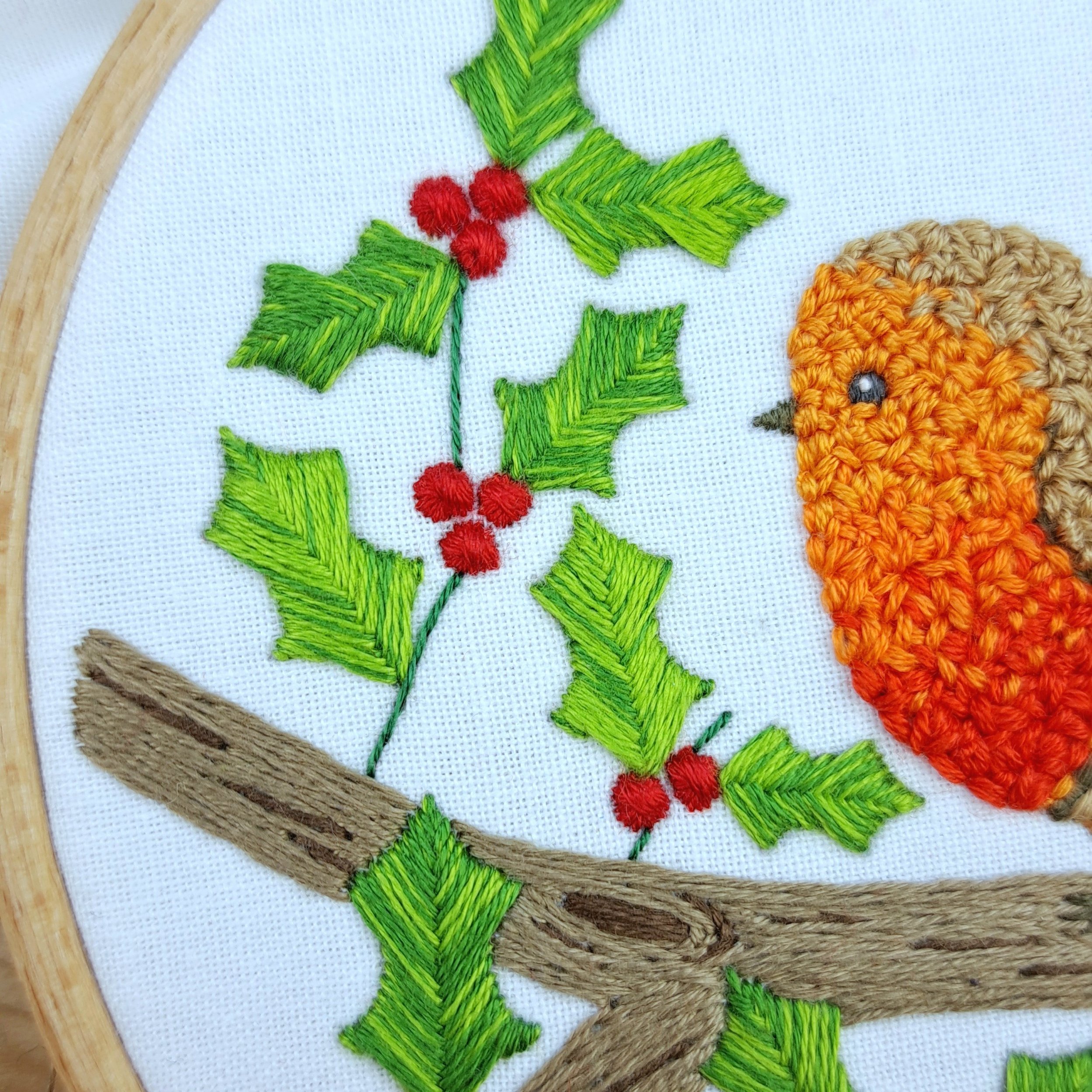 Close-up of green Stem Stitch forming small stems on the holly branch.