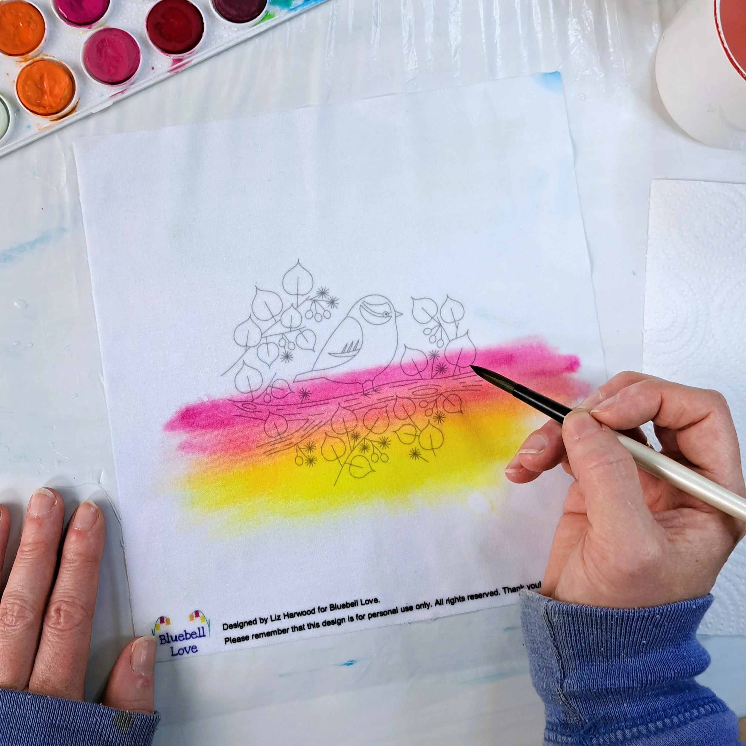 My hand painting the next colour band of sunrise to the fabric embroidery panel. There is now a band of yellow at the bottom, blending upwards into orange, and then into pink.