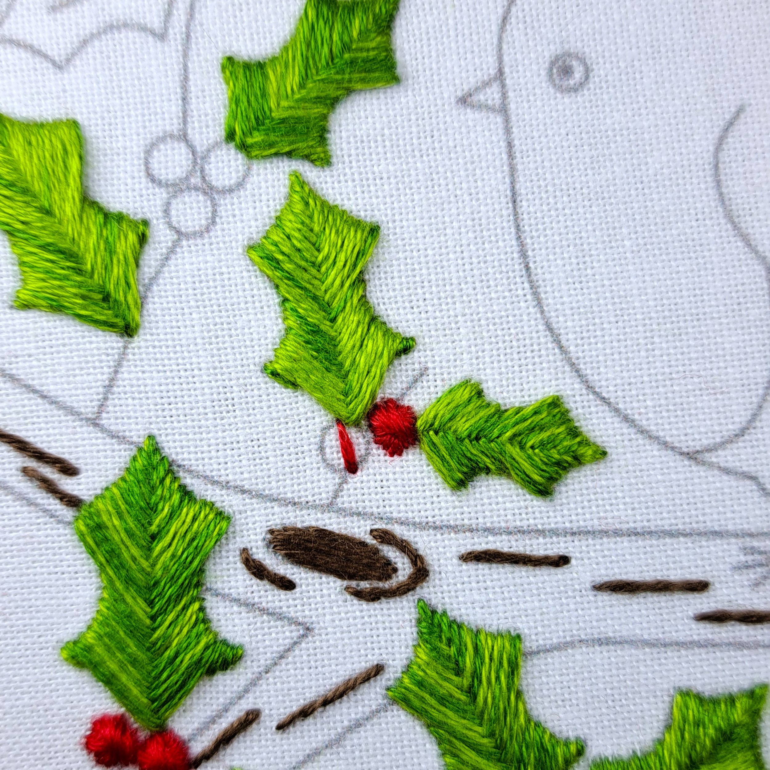 Close-up of the first red stitch in a holly berry using Rhodes Circle Stitch.