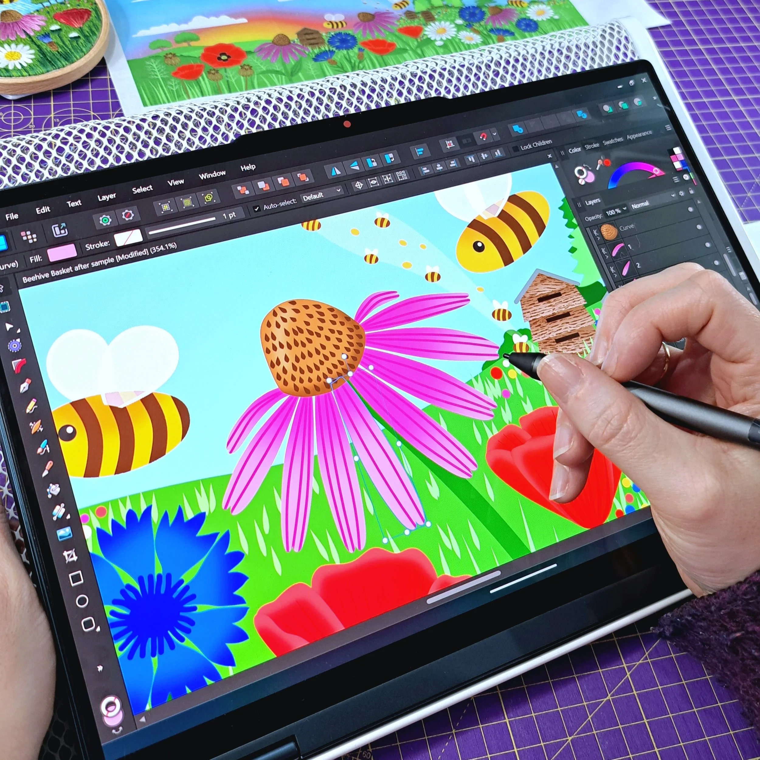 Liz illustrating embroidery designs on her laptop in the Bluebell Love studio