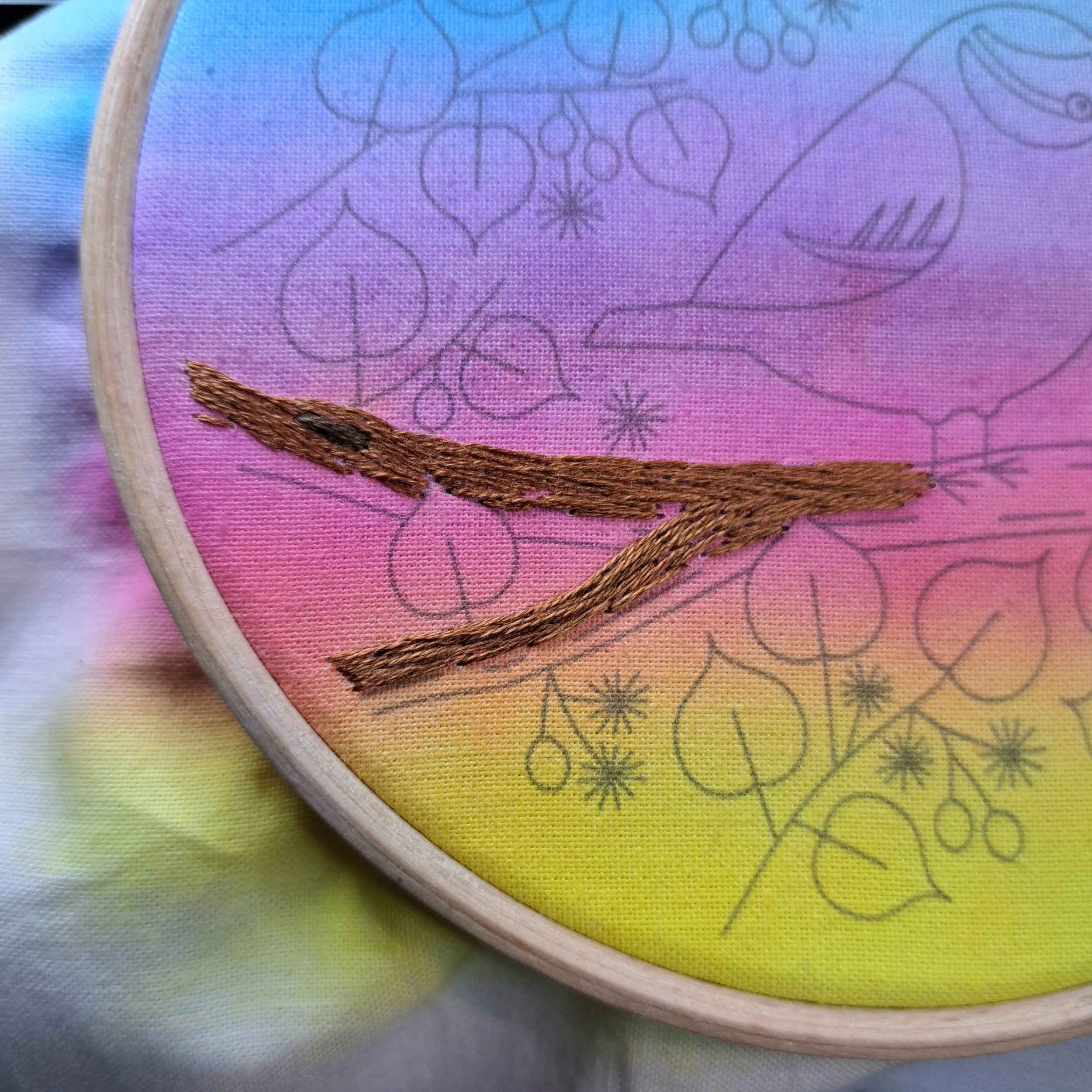 Close-up of the reddish brown Long and Short Stitch used to embroider the bark on the top half of the tree branch.