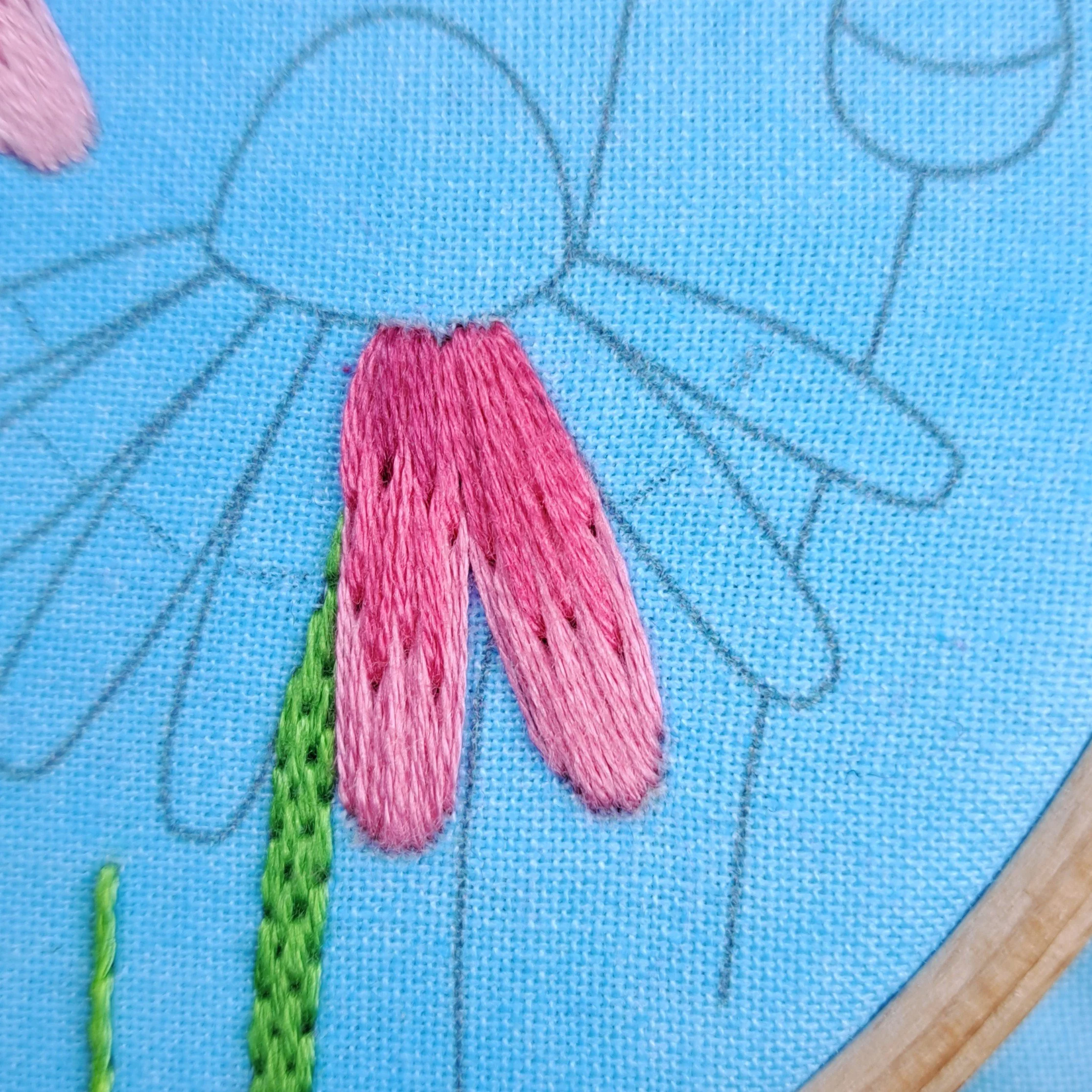 Close-up of pink satin stitch embroidered on the centre sections of the right-hand echinacea flower petals.