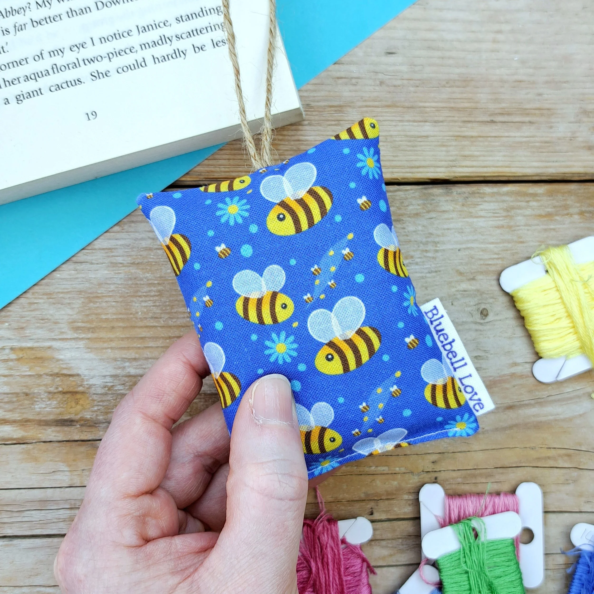 Lavender Bag sewn with a blue bee print fabric design. Lavender Bag is held in a hand.
