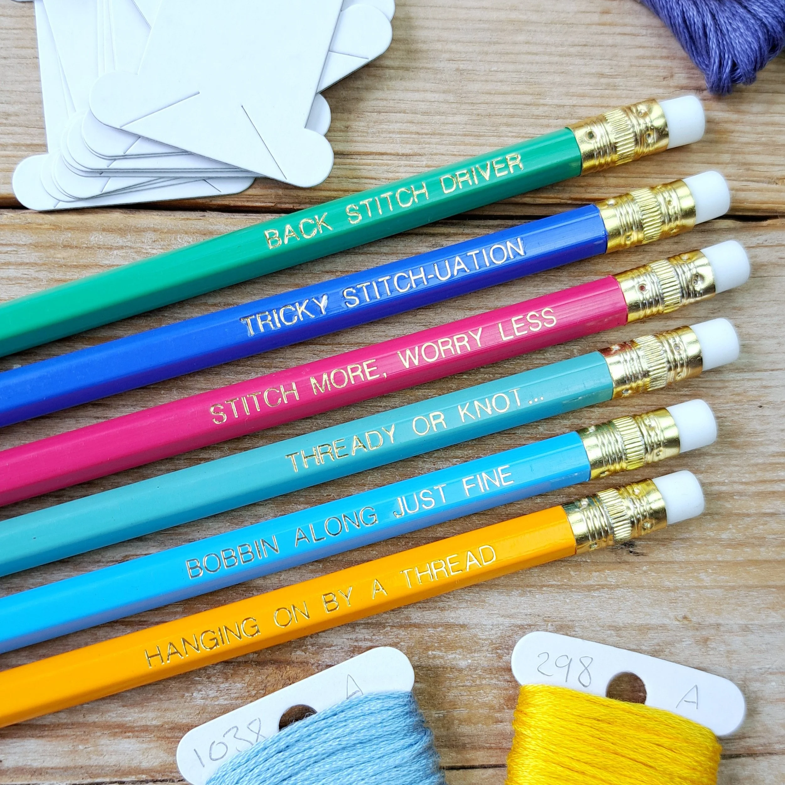 Set of six stitchy pencils showing the gold foil slogans and erasers flatlay