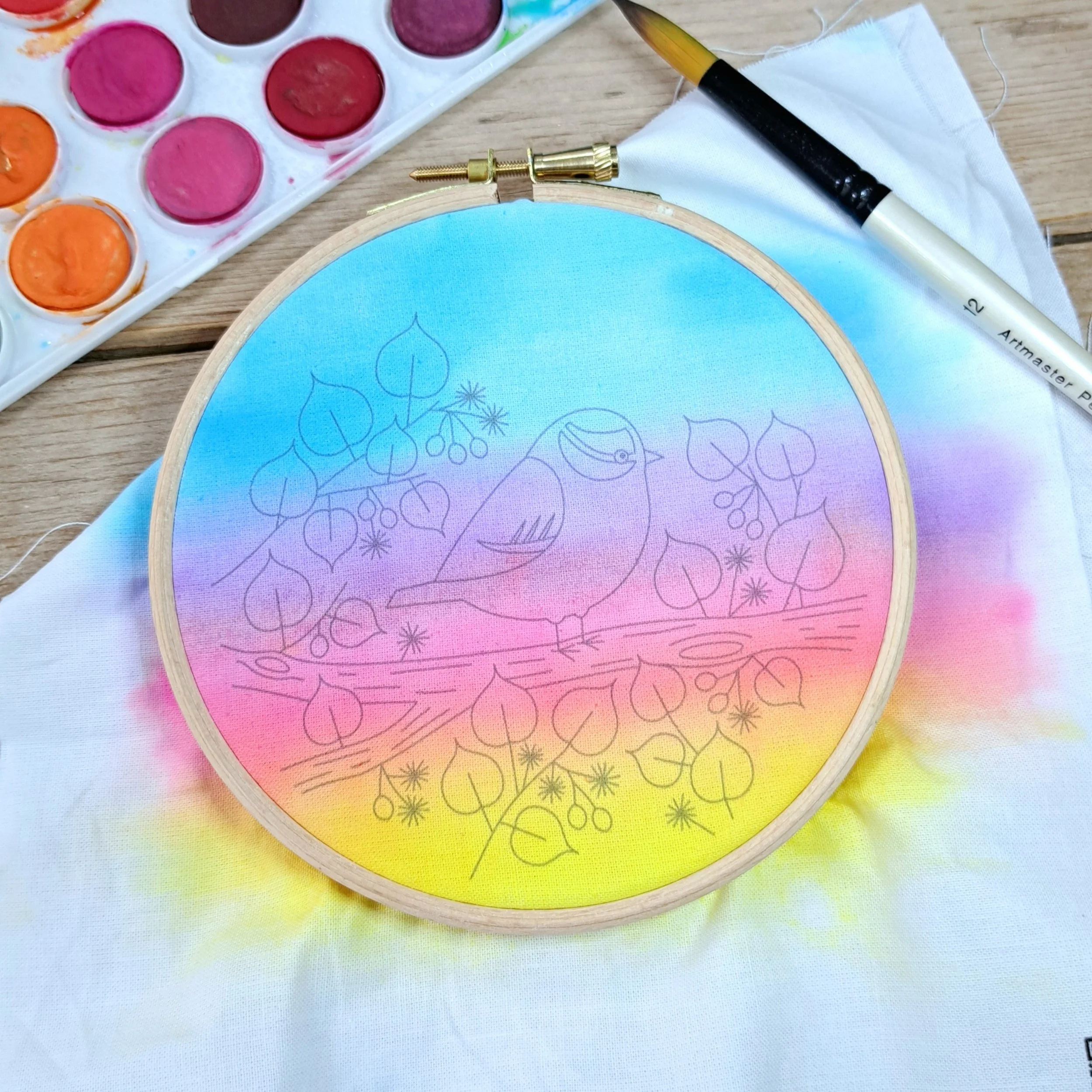 The painted bird embroidery panel dried and placed neatly in a 5-inch embroidery hoop, ready to begin stitching.