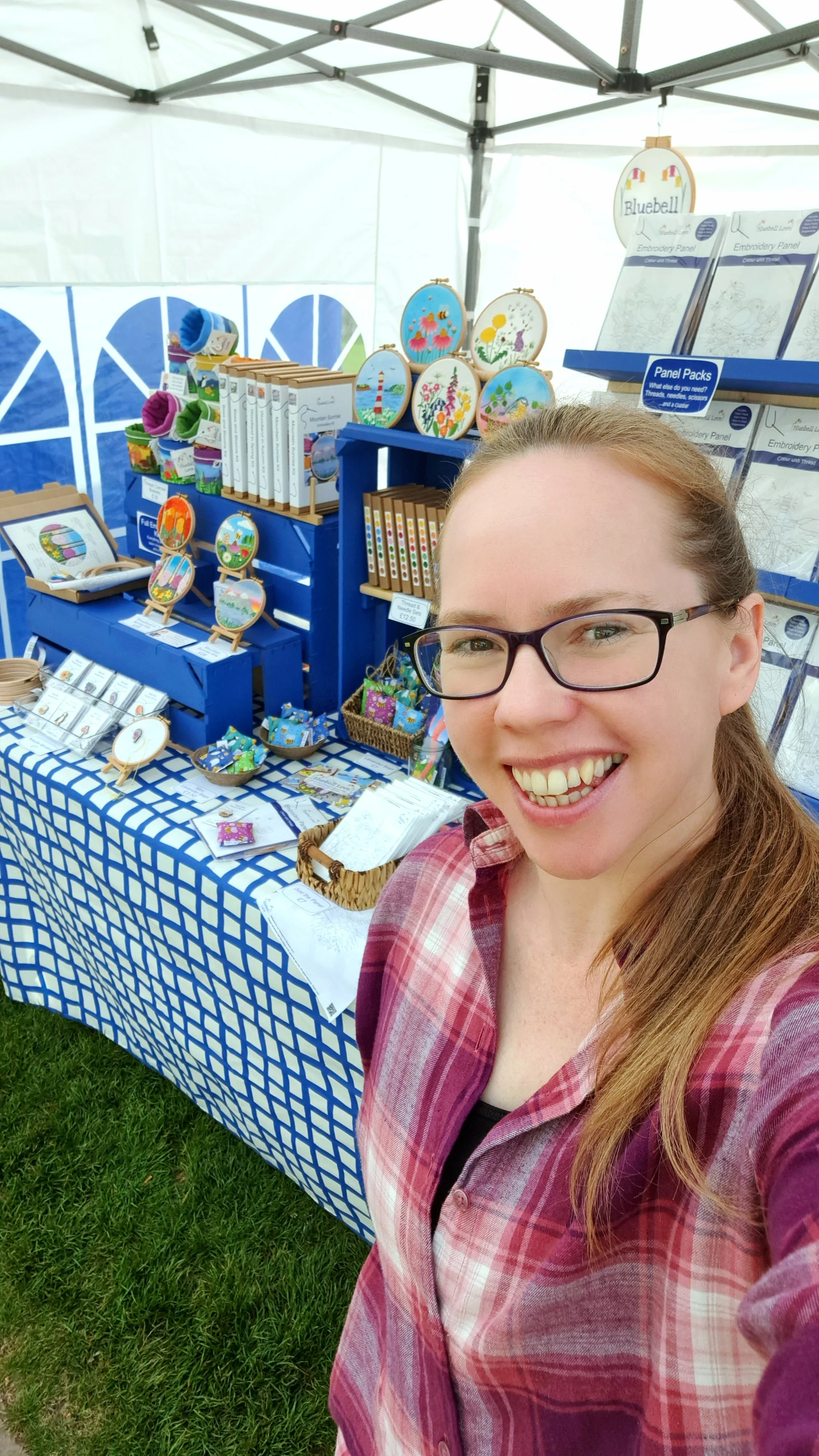 Liz from Bluebell Love standing in front of her colourful embroidery stall at a craft fair