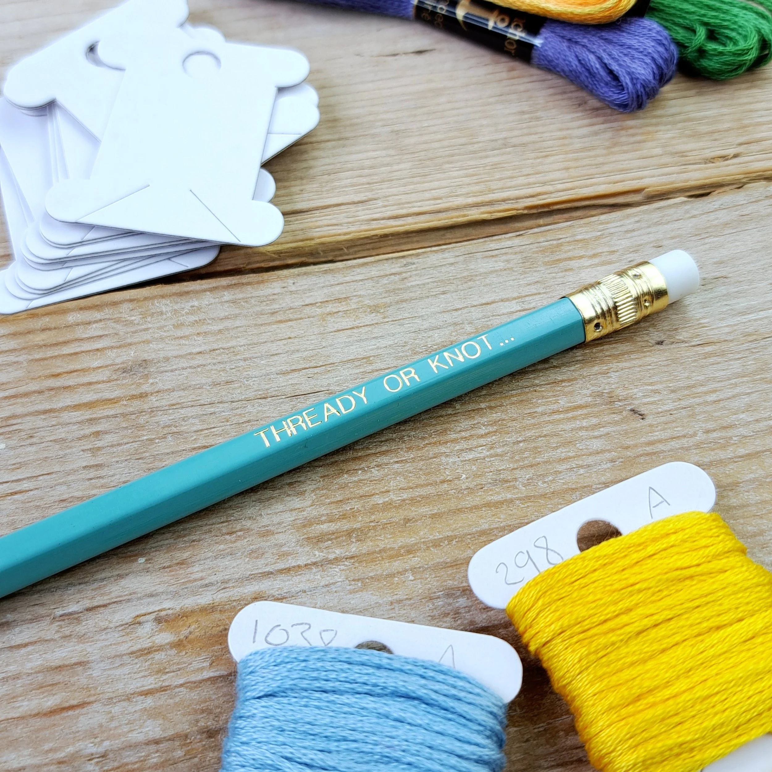 Teal "Thready or Knot" HB pencil showing the gold foil slogan, gold ferrule and white eraser