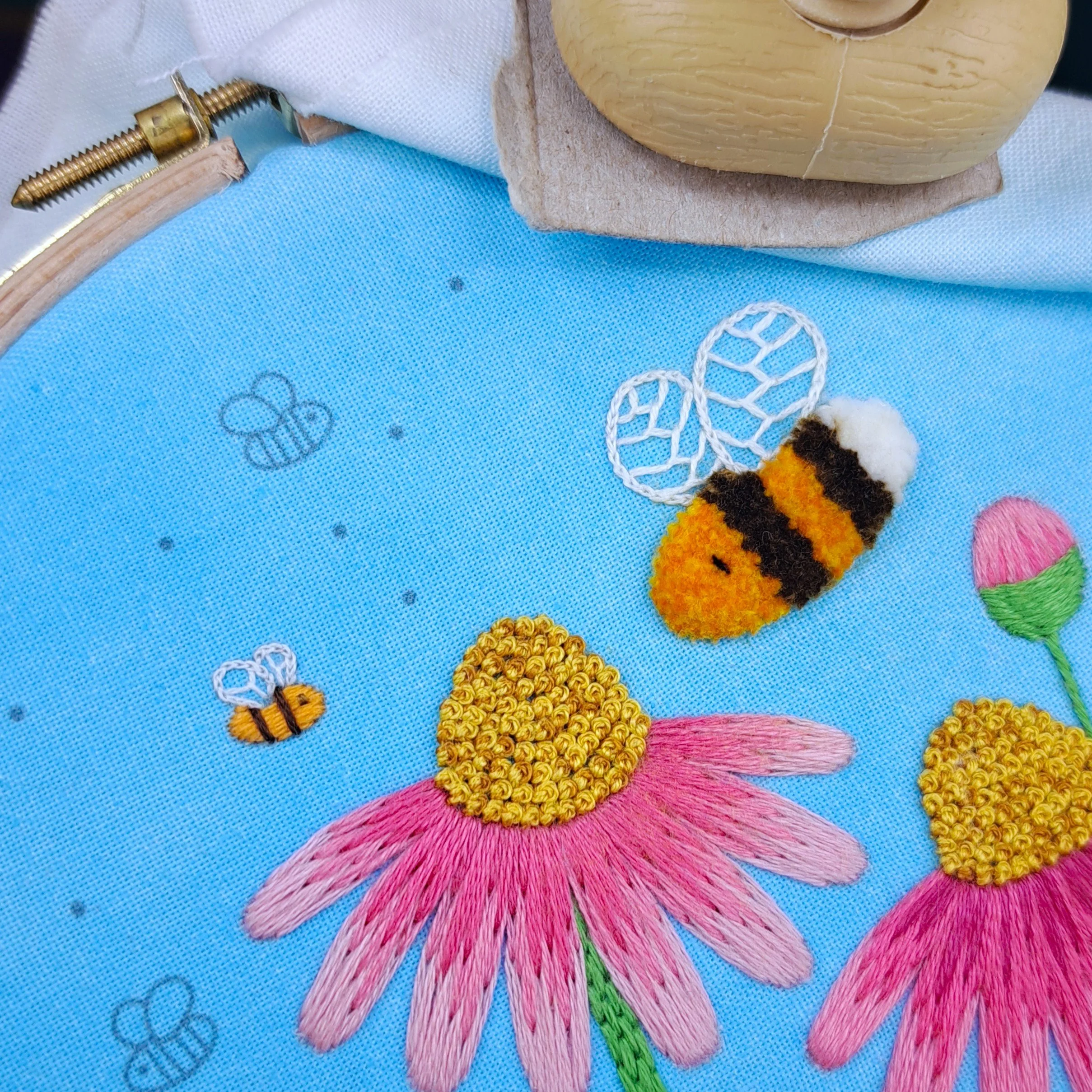Close-up of a fully stitched smaller bee together with the embroidered larger bee.