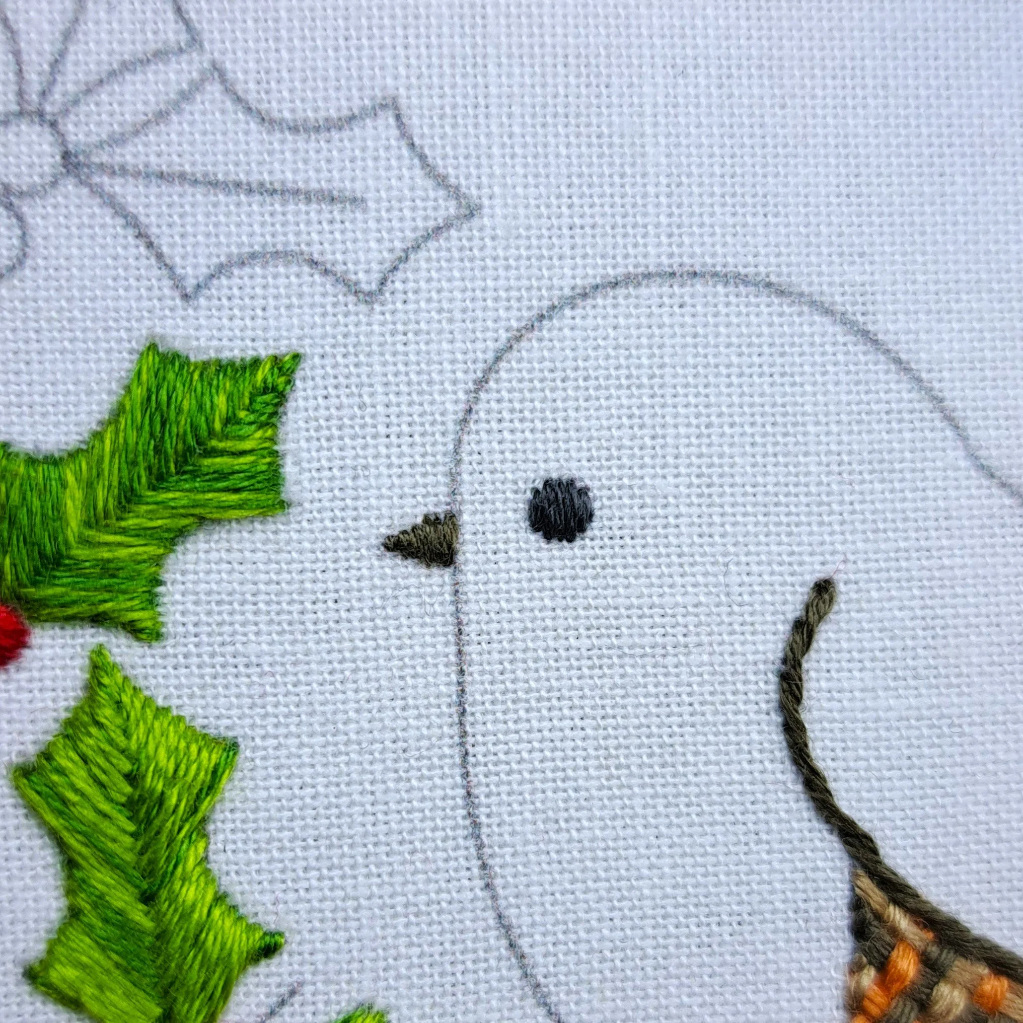 Close-up of dark grey Satin Stitch filling the robin’s eye.